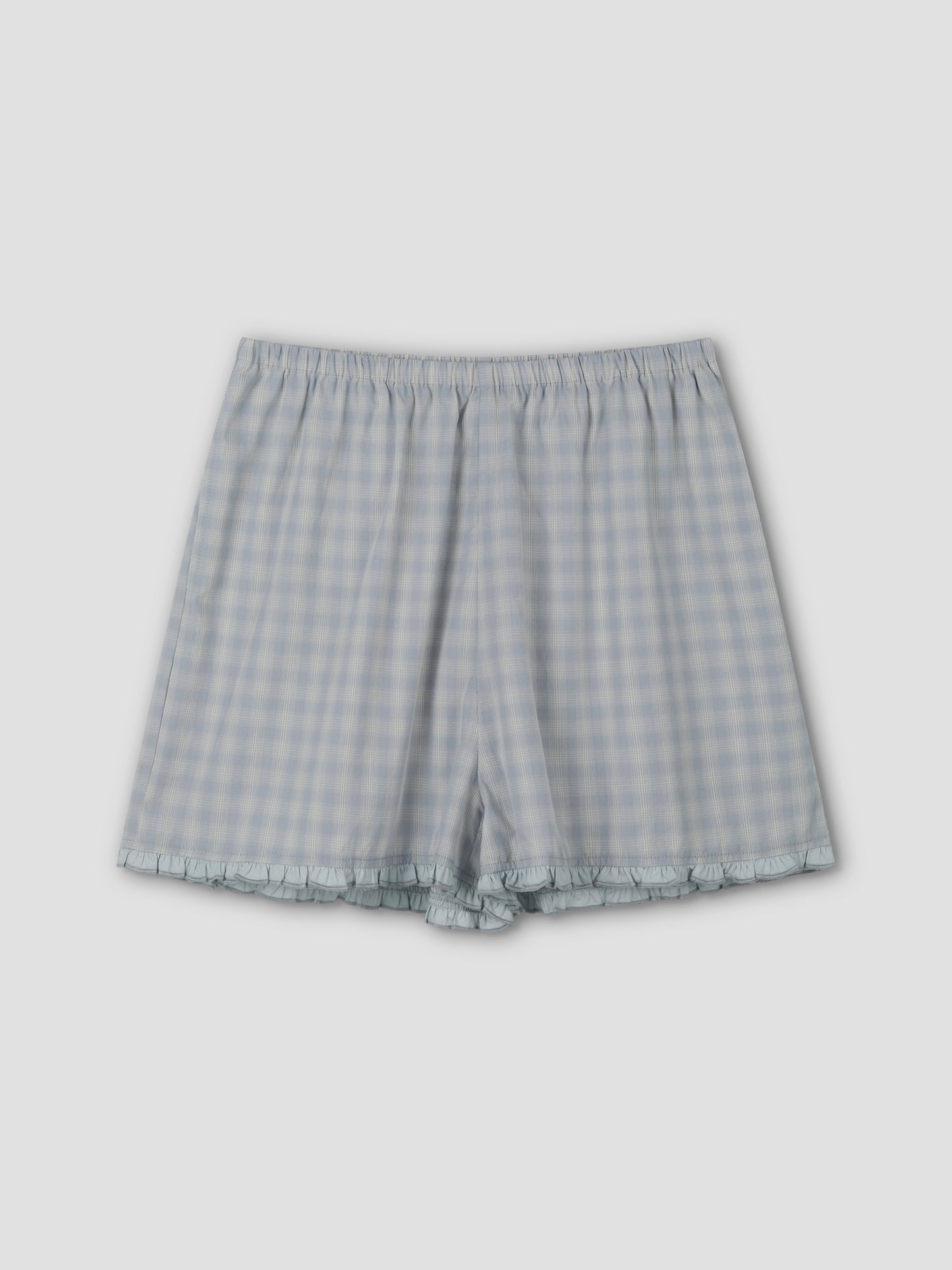 The Simple Short - Blue Check features a relaxed fit, elastic waistband, and subtle ruffle trim at the hem, shown flat on a plain light gray background.