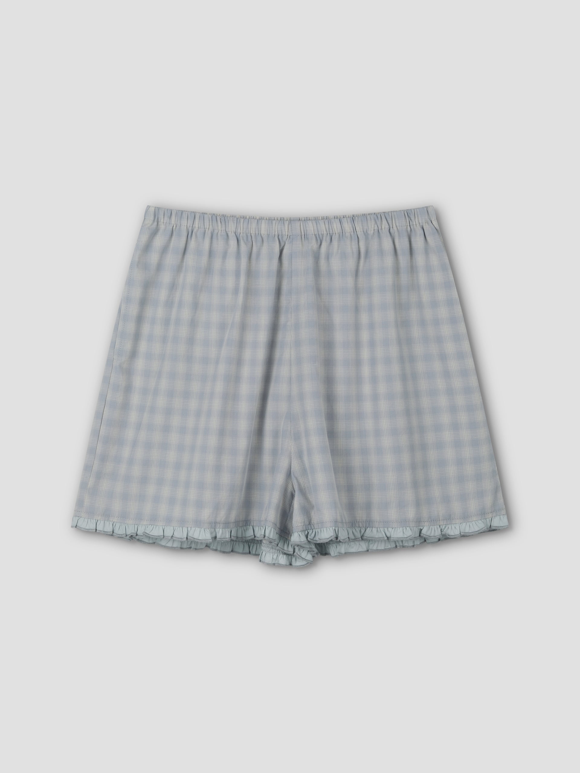 The Simple Short - Blue Check features a relaxed fit, elastic waistband, and subtle ruffle trim at the hem, shown flat on a plain light gray background.
