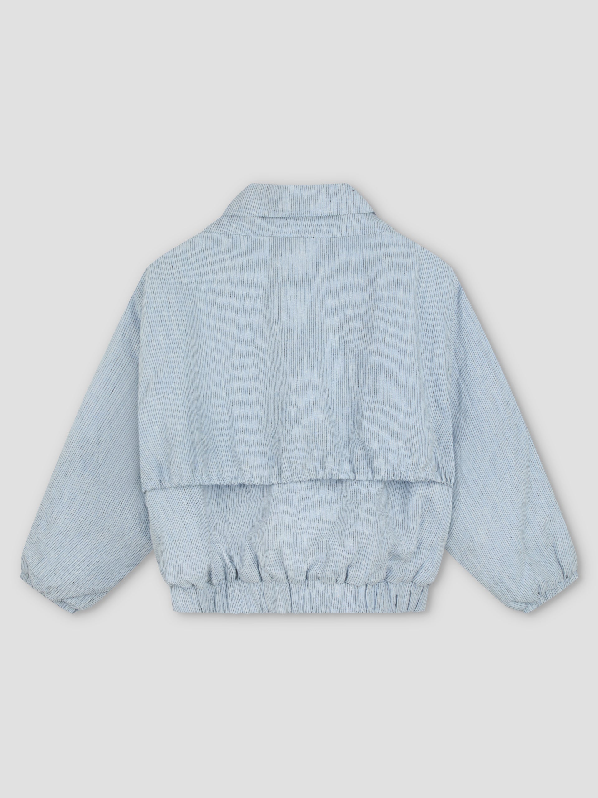 The Double Layered Jacket - Blue Stripe by Deiji Studios is a light blue, long-sleeve padded bomber with subtle vertical stripes, elastic cuffs, waistband, and a collar, shown from the back against a light gray background.