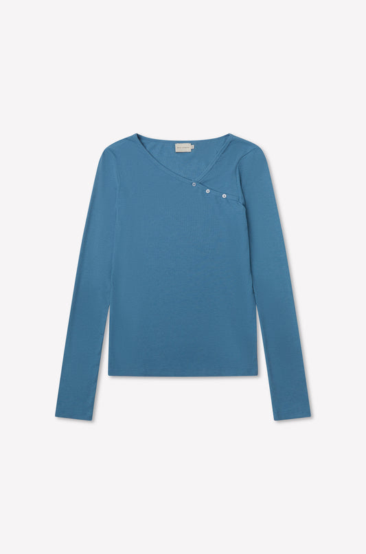 The Multi Button Top - Aqua by deiji studios is a fitted long sleeve jersey in blue with an asymmetrical neckline and three small buttons on the upper right, shown on a plain white background.