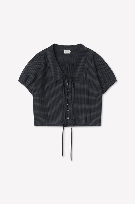 The Fine Collar Top - Mono Grid is a short-sleeved, charcoal gray cotton poplin top with a subtle grid pattern, collared v-neck, and drawstring at the cropped hem, shown laid flat on a white background.