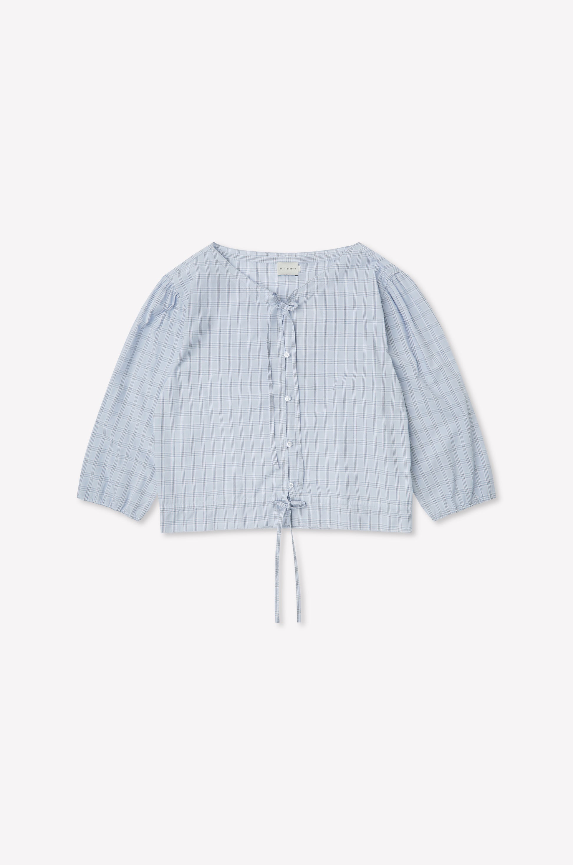 The Corded Top - Powder Check features a light blue, long sleeve design with a subtle check pattern, button-up front, V-neckline, drawstring waist, and slightly puffed sleeves. Inspired by Deiji Studios. Displayed flat on a white background.