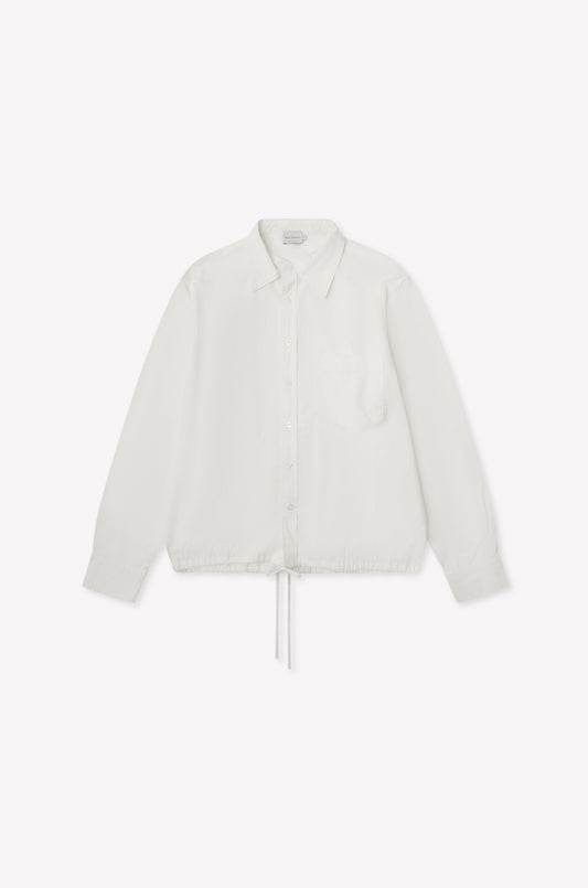 The Stand Shirt - White is a long-sleeved, oversized cotton shirt featuring a single chest pocket, mandarin collar, and drawstring hem, shown on a white background.