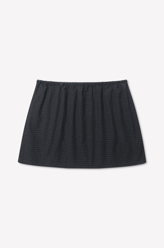 A black mini skirt with an elastic waistband and a subtle textured grid pattern, perfect for pairing with the Flow Top - Mono Grid, displayed on a plain white background.