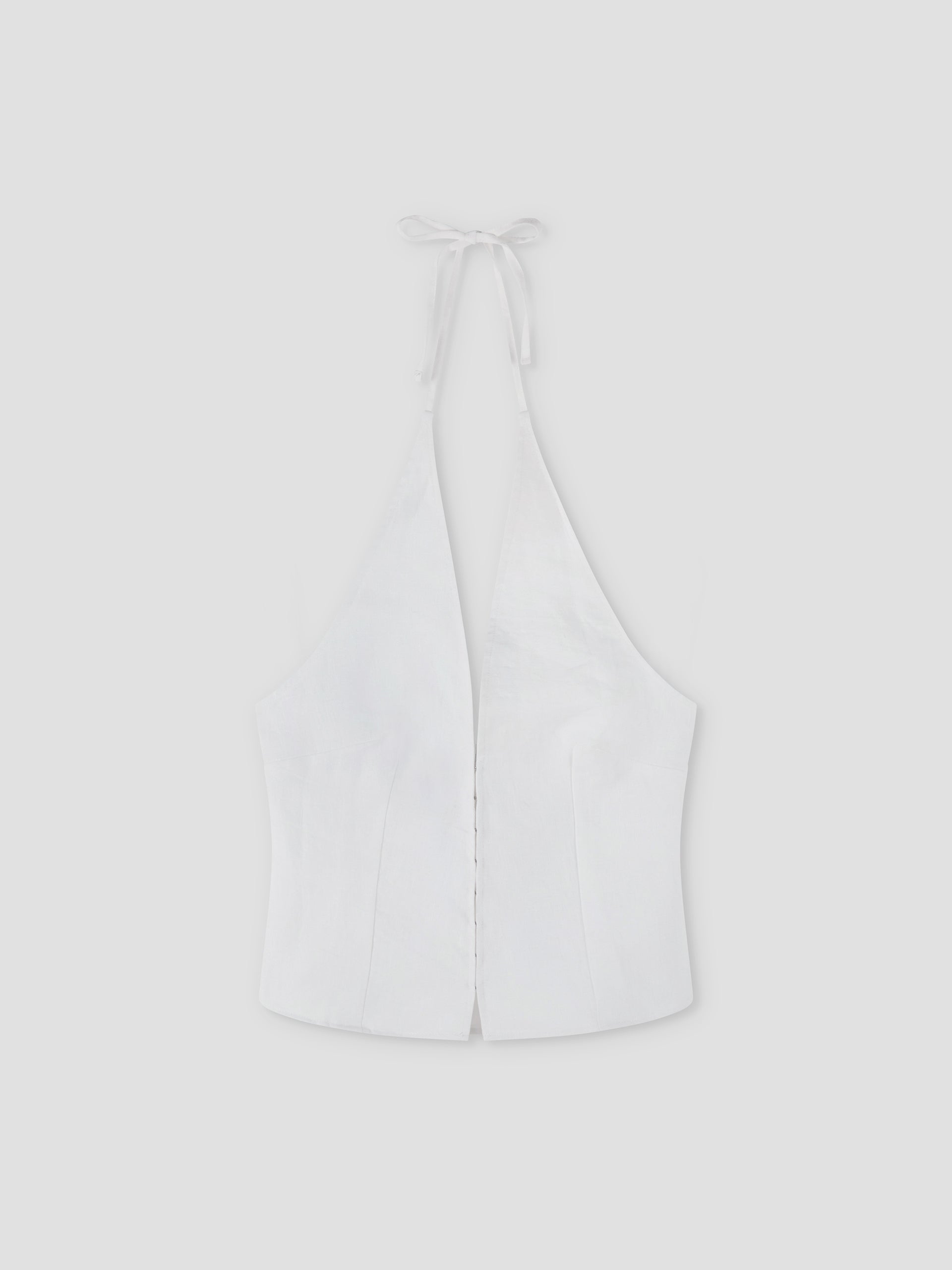 The Close Halter Top - White by Deiji Studios features a deep V neckline, fitted bodice, and open back with neck ties. Displayed on a plain light gray background, it highlights clean, minimalist elegance.