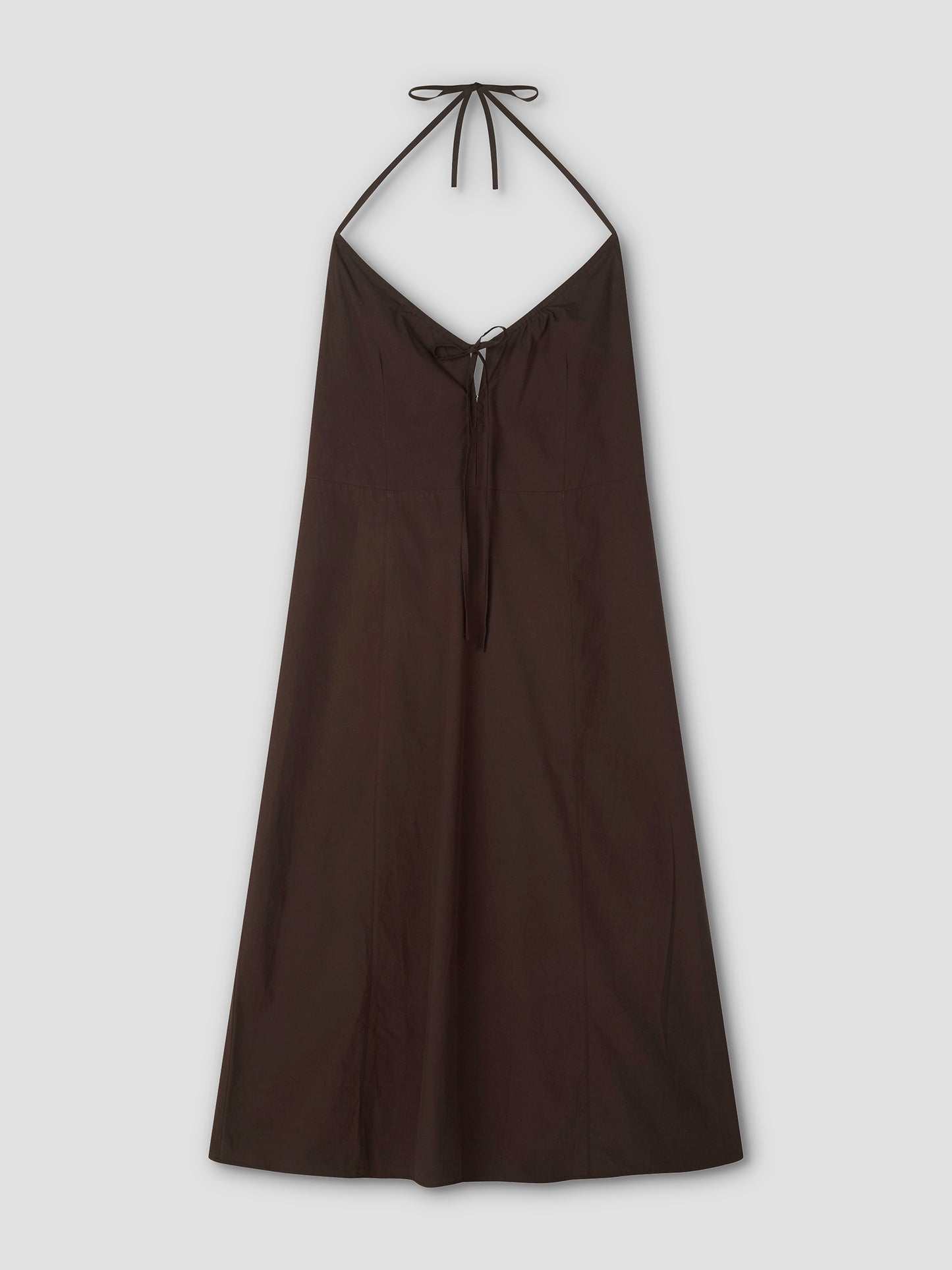 The Seamed Halter Dress - Sepia by Deiji Studios is a sleeveless, dark brown (sepia) A-line midi dress featuring seamed details, a V-neckline, and thin halter straps that tie at the neck. Shown against a light gray background.