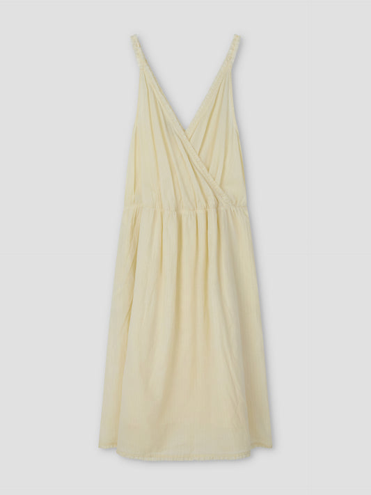 The Crossed Dress - Soft Yellow Stripe by Deiji Studios features a sleeveless, relaxed-fit design with a crossover v-neckline, gathered waist, and knee-length hem in lightweight striped fabric—perfect for effortless style.