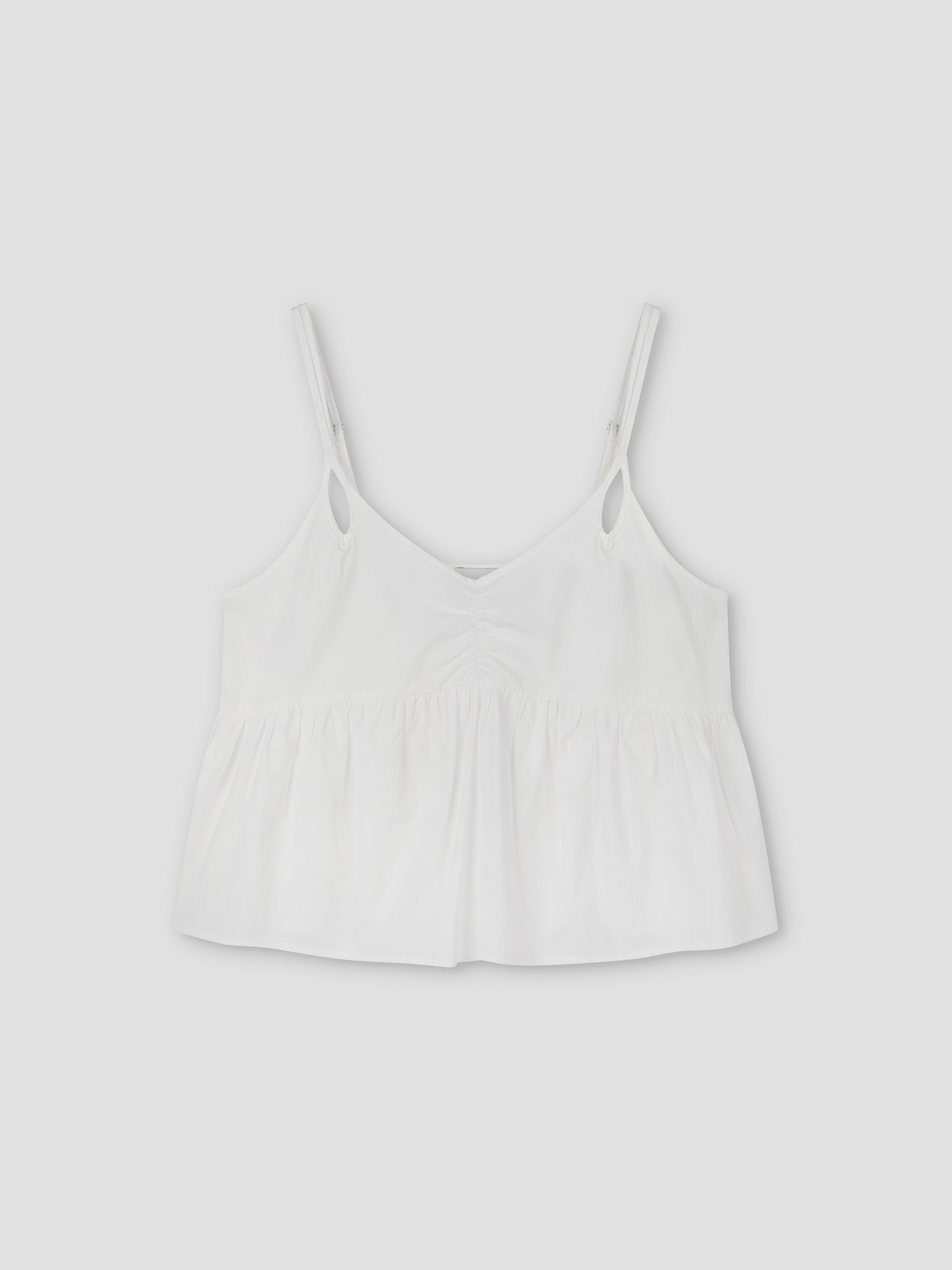 The Bind Top - White is a cami-style top with thin straps, a v-neckline, gathered fabric below the bust, and a loose, flowy fit inspired by Deiji Studios. Shown on a plain light background.