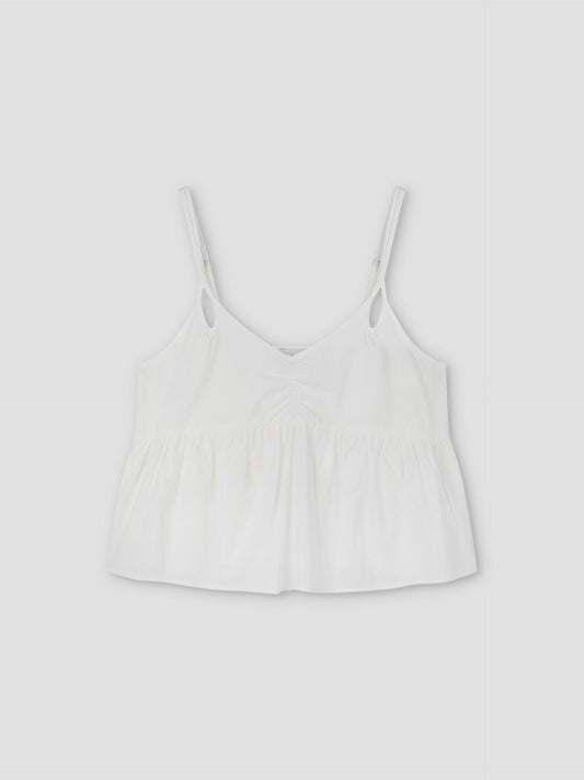 The Bind Top - White is a cami-style crop top with thin straps, a loose fit, and a gathered ruffled hem. This lightweight Deiji Studios piece has a simple silhouette, shown on a plain light gray backdrop.