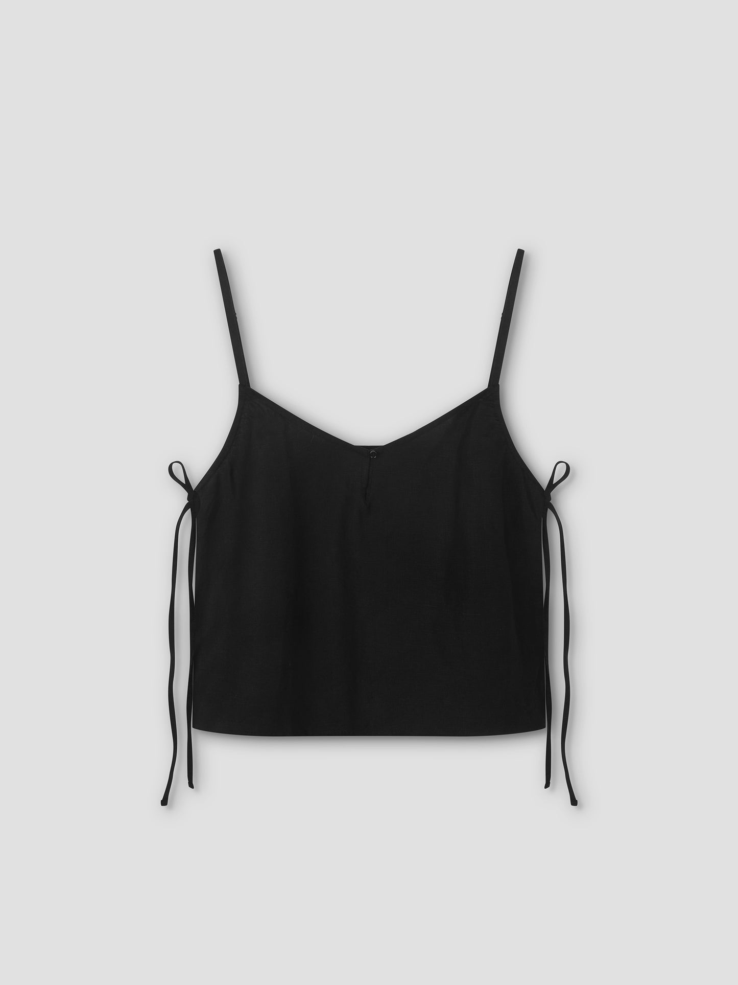 The V Neck Cami - Black features thin spaghetti straps, a v-neckline, and adjustable side ties. Inspired by lightweight cami silhouettes for effortless style, it's shown against a light gray background.