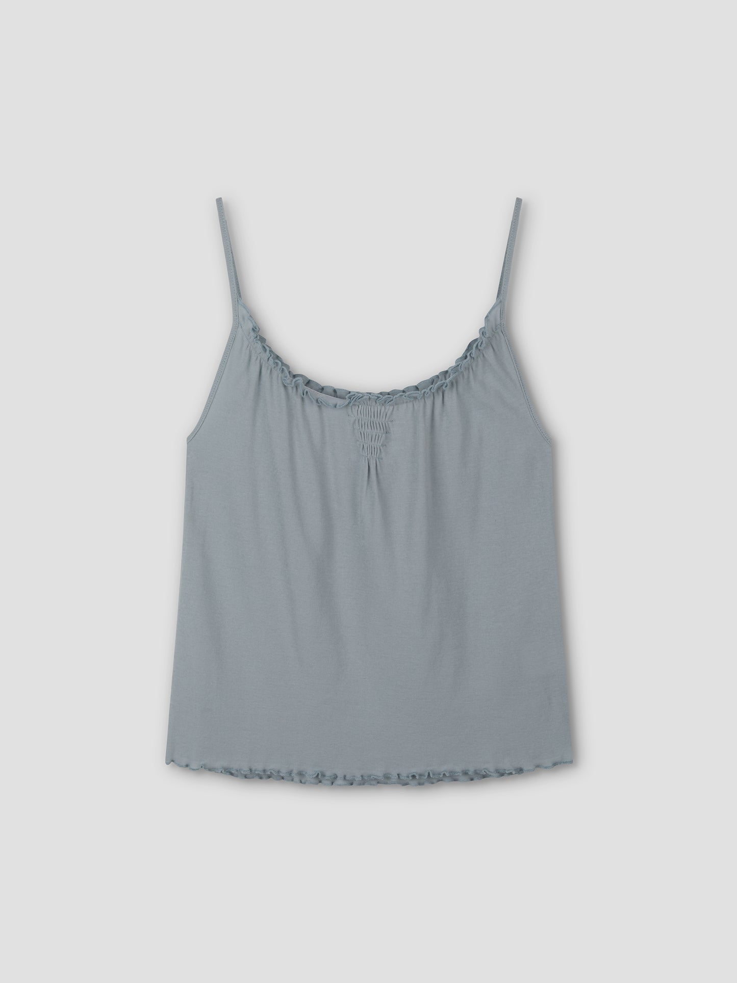 The Cotton Flounce Tank - Baby Blue by Deiji Studios features thin spaghetti straps, a slight scoop neckline, and delicate ruffle details at the neckline and hem, shown laid flat against a plain light background.