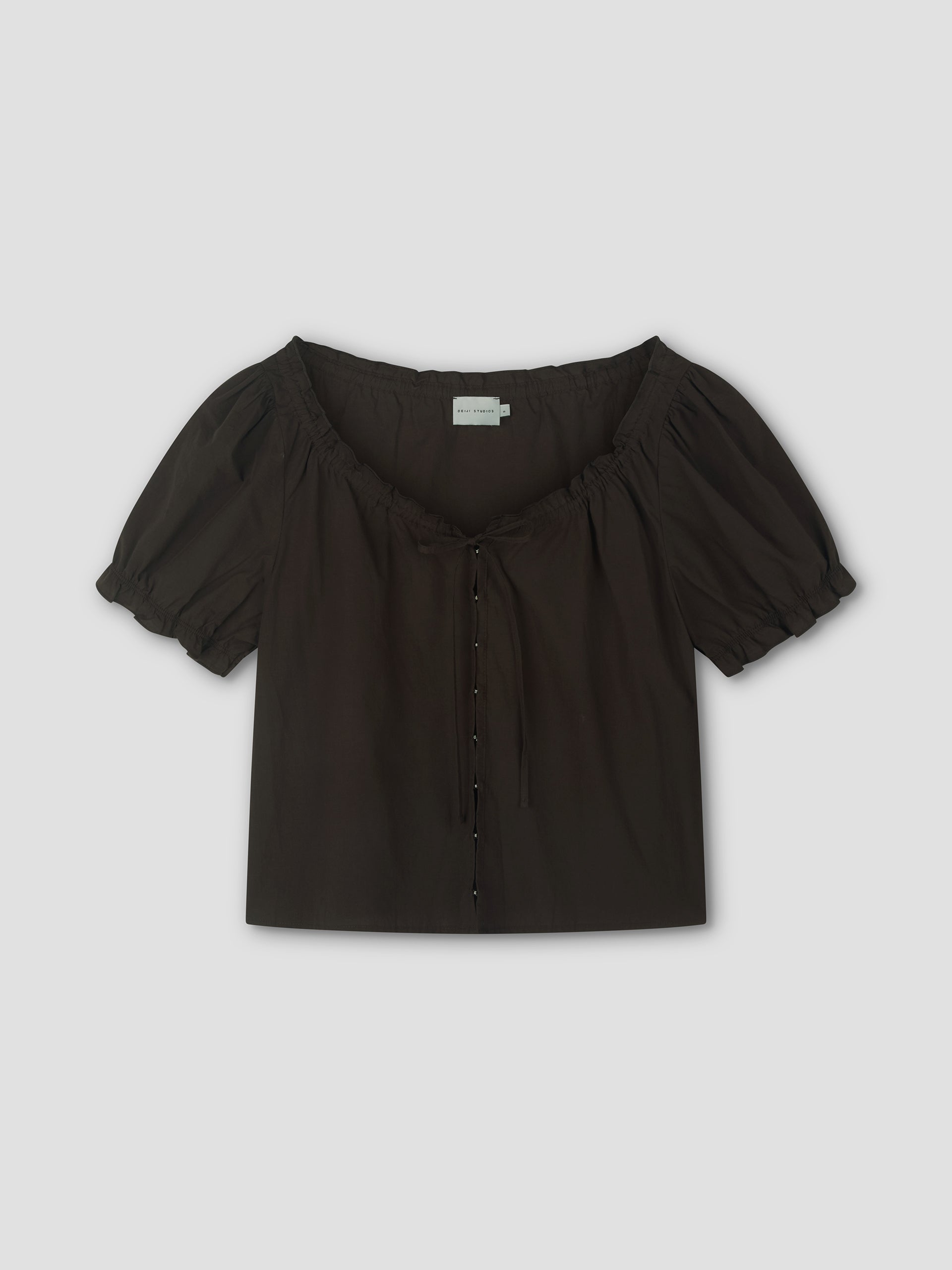 The Close Shirt - Sepia by Deiji Studios is a black, short-sleeved, square-neck blouse with puffed sleeves, a gathered neckline, small buttons and ties down the front, shown cropped and relaxed against a light background.