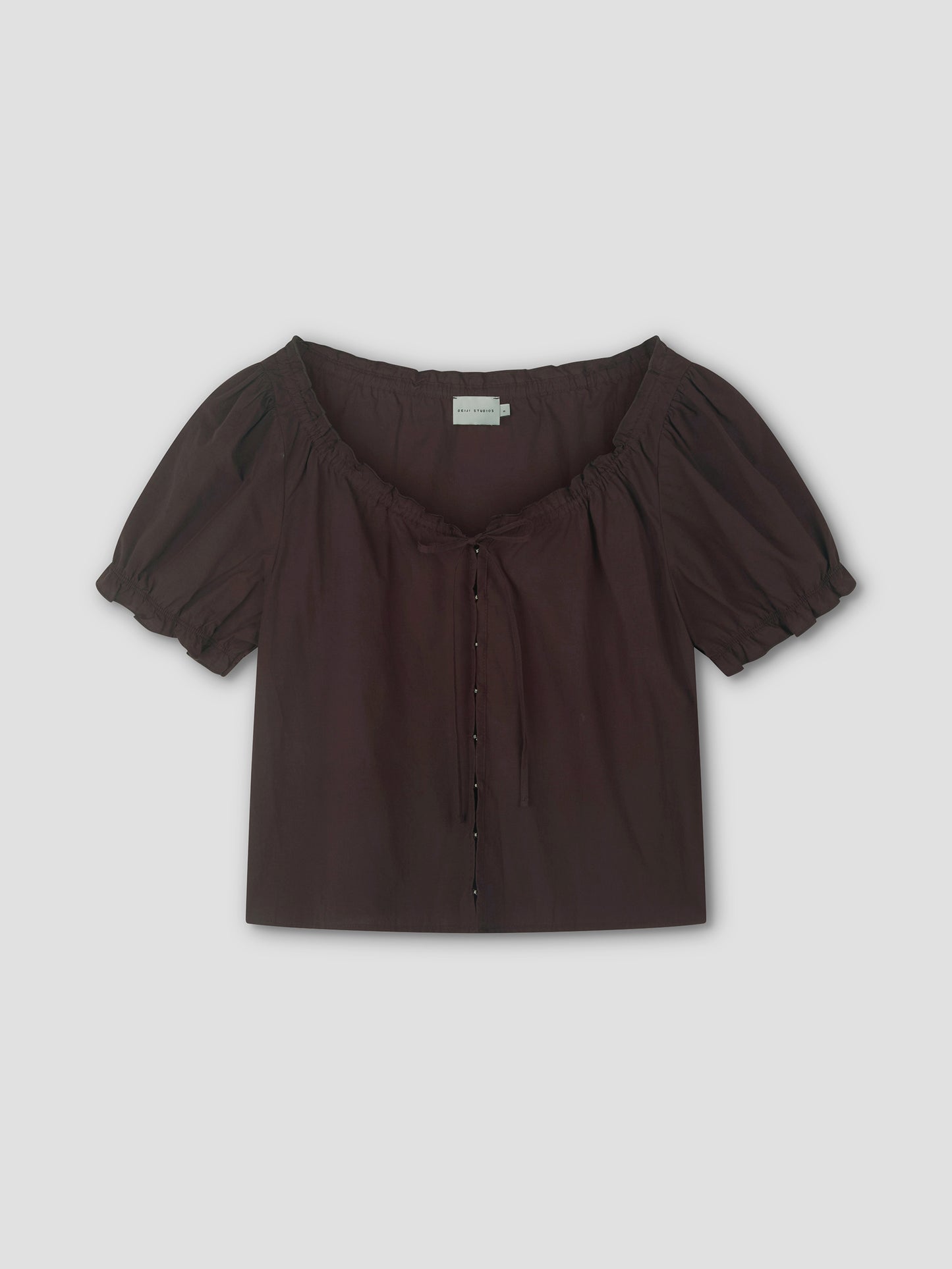 The Close Shirt - Sepia by Deiji Studios is a short-sleeved, dark brown blouse featuring a square neckline, puff sleeves with gathers, a drawstring neckline tie, and button-down front, shown on a plain light background.