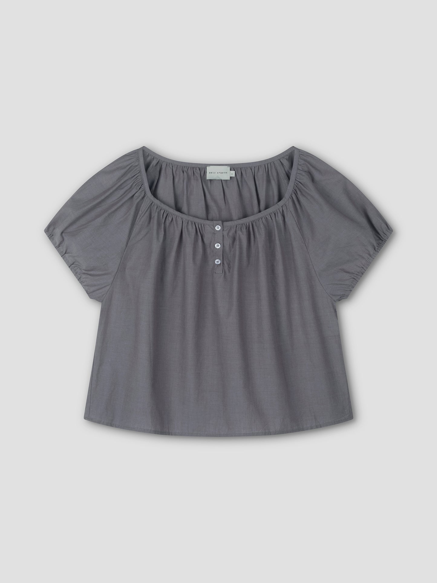 The Poplin T Shirt - Currant features short sleeves, a loose fit, a wide scoop neckline, and three front buttons, inspired by Deiji Studios’ cropped relaxed silhouette. Shown on a plain light grey background.