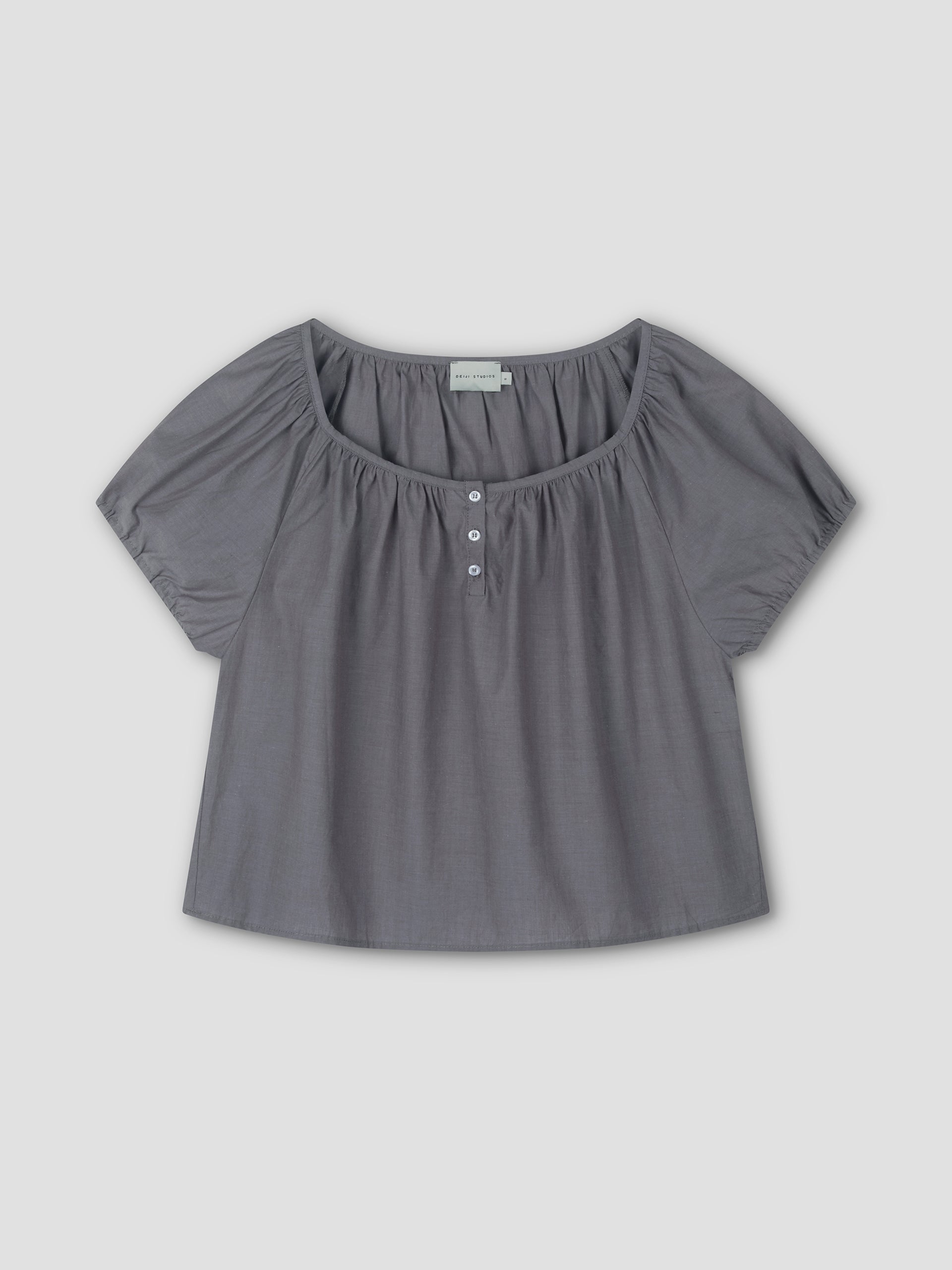 The Poplin T Shirt - Currant features short sleeves, a loose fit, a wide scoop neckline, and three front buttons, inspired by Deiji Studios’ cropped relaxed silhouette. Shown on a plain light grey background.