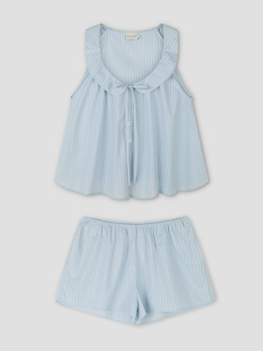 The Round Collar Set - Lake Blue Stripe is a sleeveless pajama set with white and blue stripes, round collar, front buttons, a bow detail, and loose-fit matching shorts. Inspired by Deiji Studios with soft, lightweight fabric.