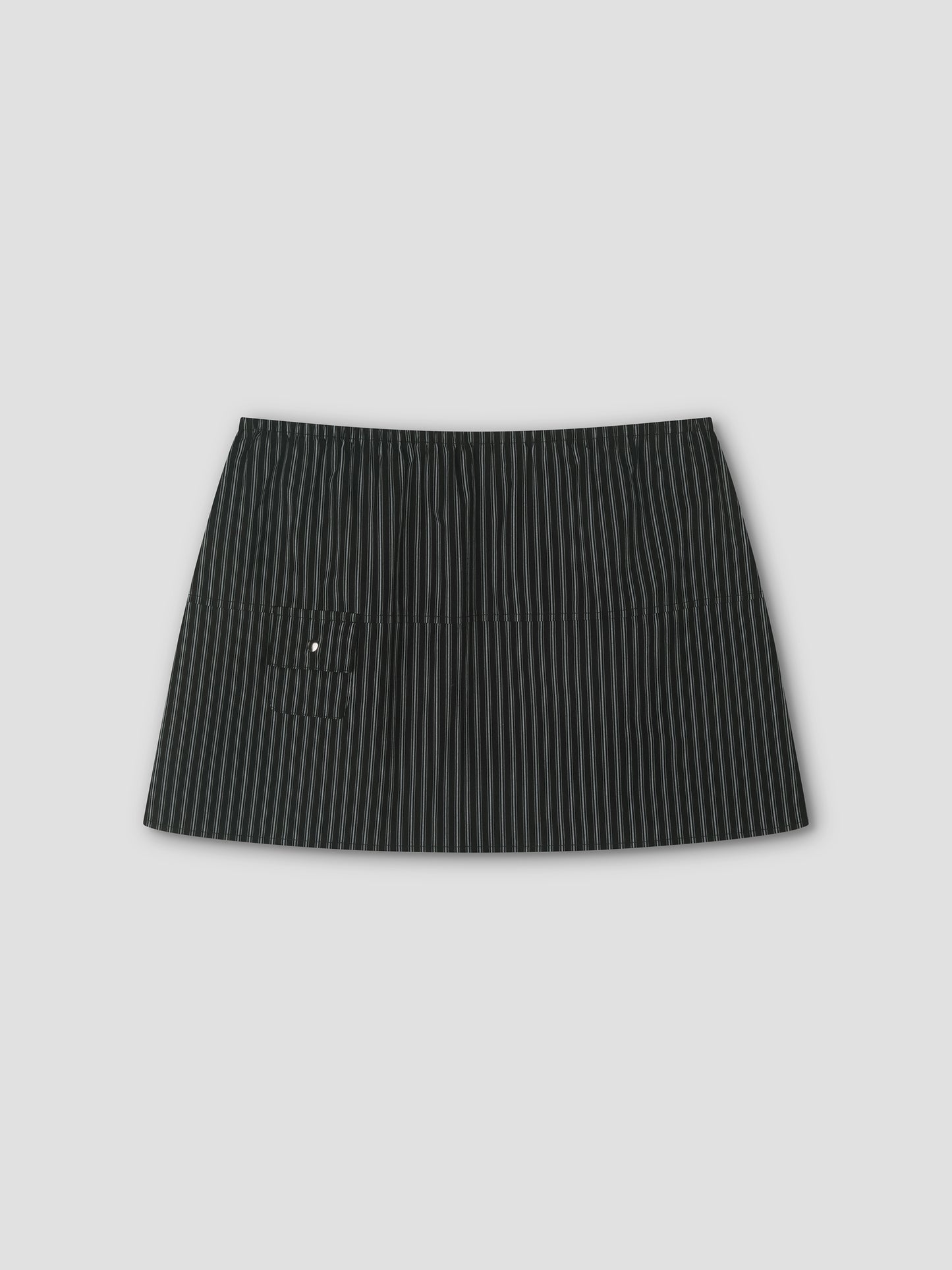 The Pocket Skirt - Mono Stripe is a black mini skirt with thin white pinstripes, an elastic waistband, and a small left front pocket, shown against a plain light gray background.