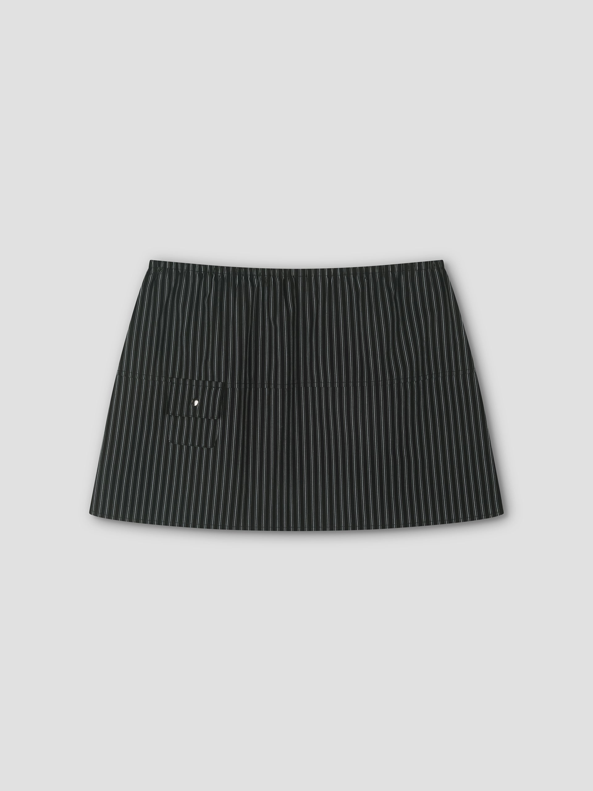 The Pocket Skirt - Mono Stripe is a black mini skirt with thin white pinstripes, an elastic waistband, and a small left front pocket, shown against a plain light gray background.