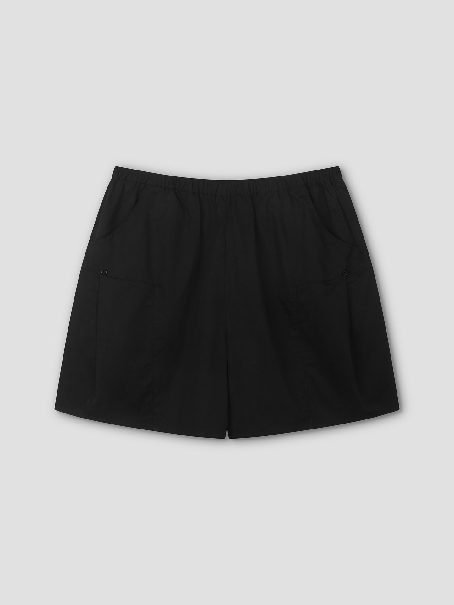 The Pleat Short - Black features a relaxed mid-rise fit, elastic waistband, and two front pockets, shown flat on a light grey background—a minimalist staple by Deiji Studios.