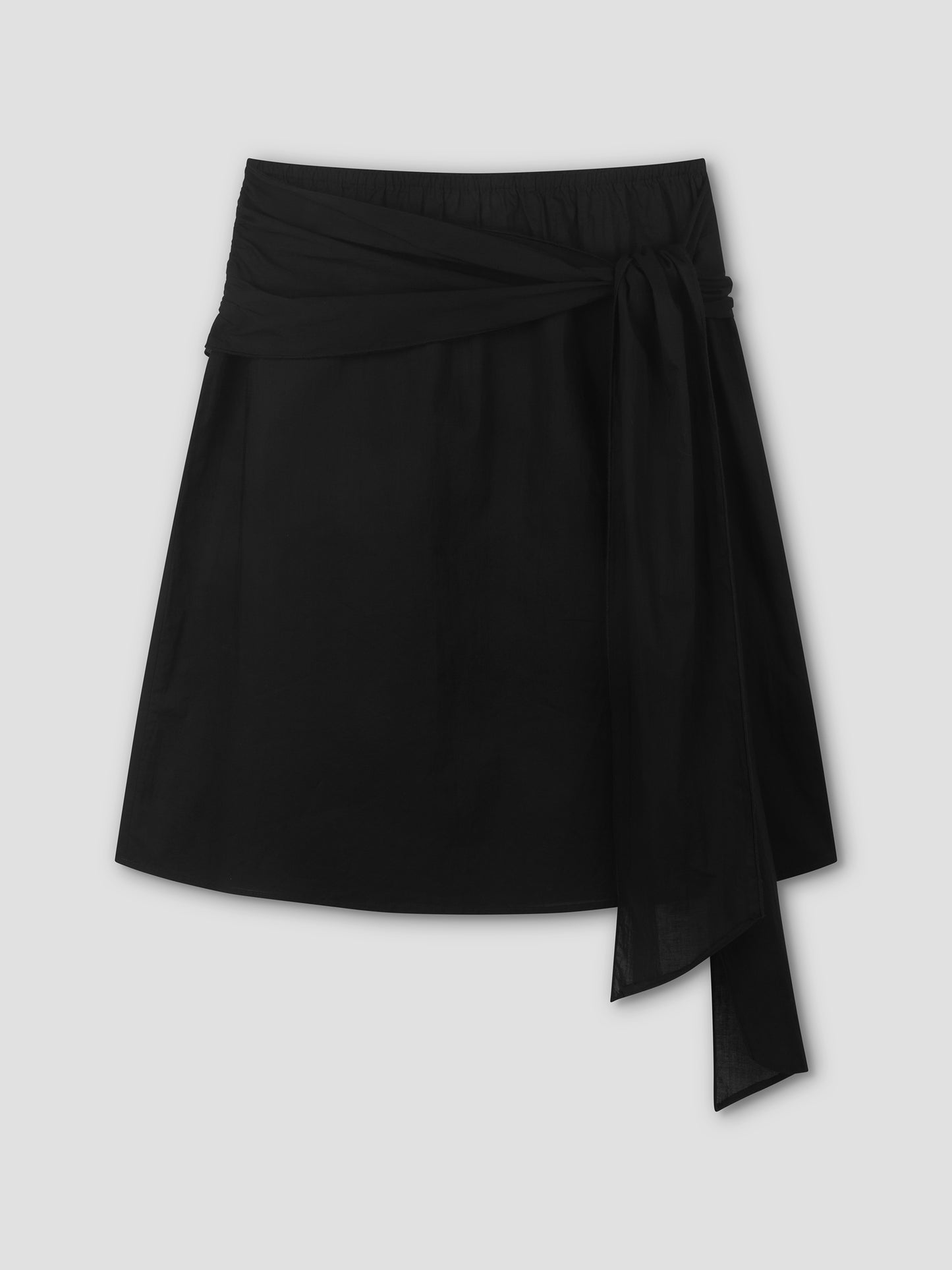 The Scarf Midi - Black by Deiji Studios is a short black skirt featuring a wide waistband and a long draped tie on the right side, shown against a plain light gray background.