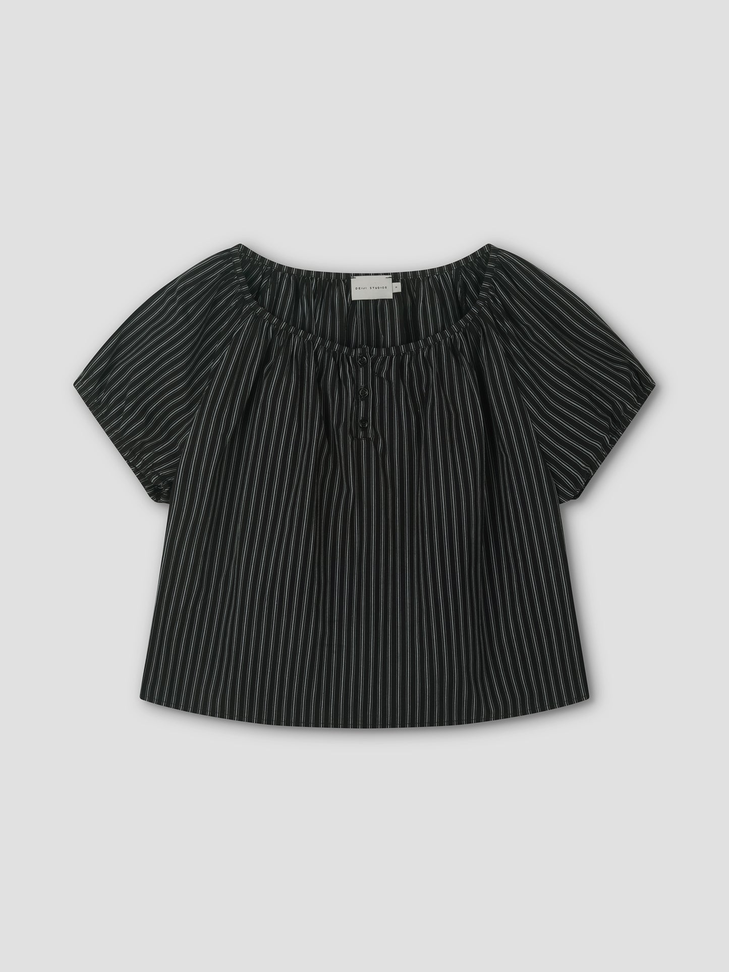 The Poplin T Shirt - Mono Stripe is a black short-sleeve blouse with white stripes, a loose fit, elastic gathered neckline, and center tie, styled like Deiji Studios. It’s displayed flat on a light gray background.