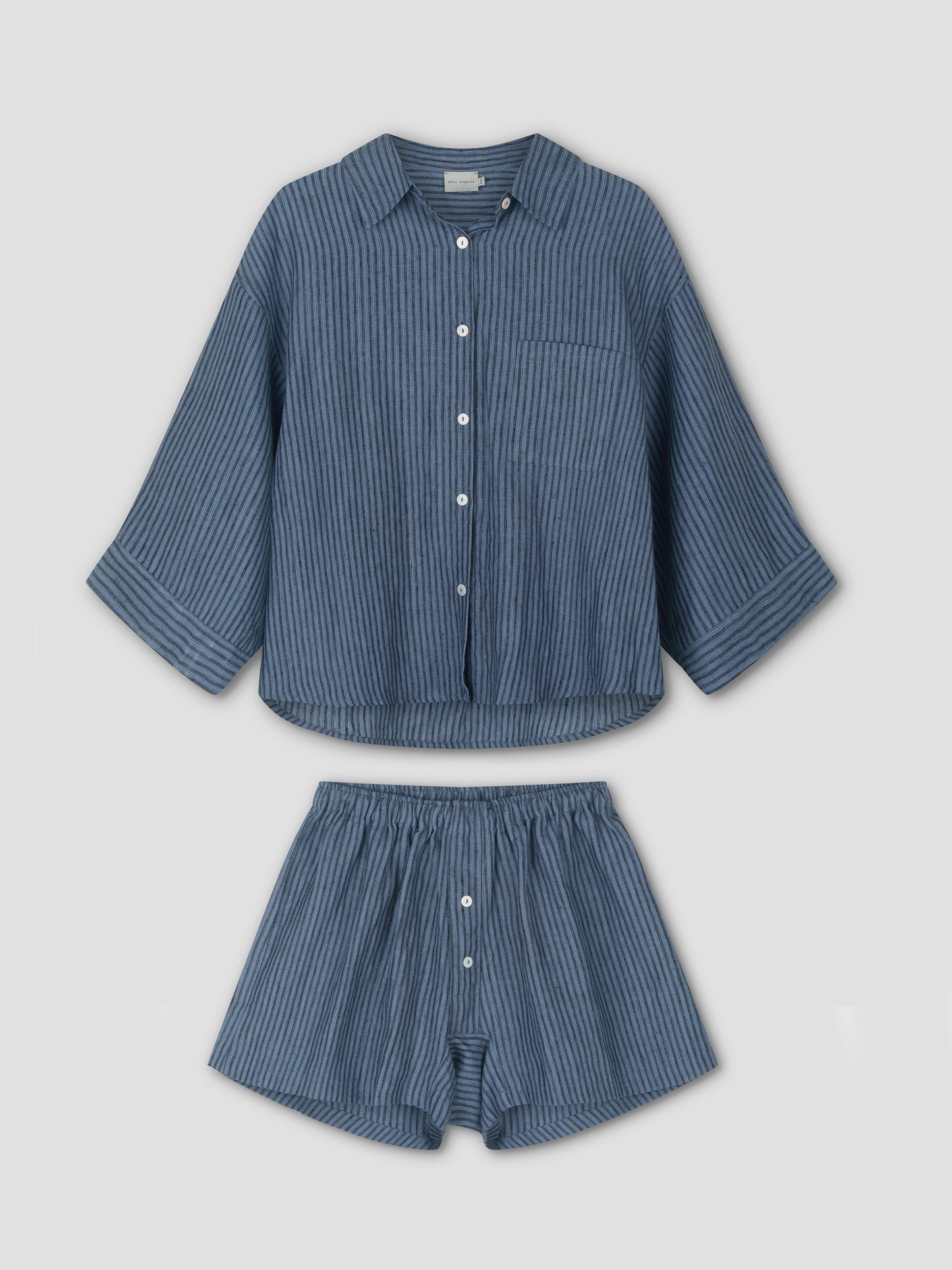 The 03 Set - Azure Stripe from Deiji Studios: blue pinstriped linen pajamas with a long-sleeve, button-up shirt and elastic-waist boxer shorts, both displayed flat on a white background.