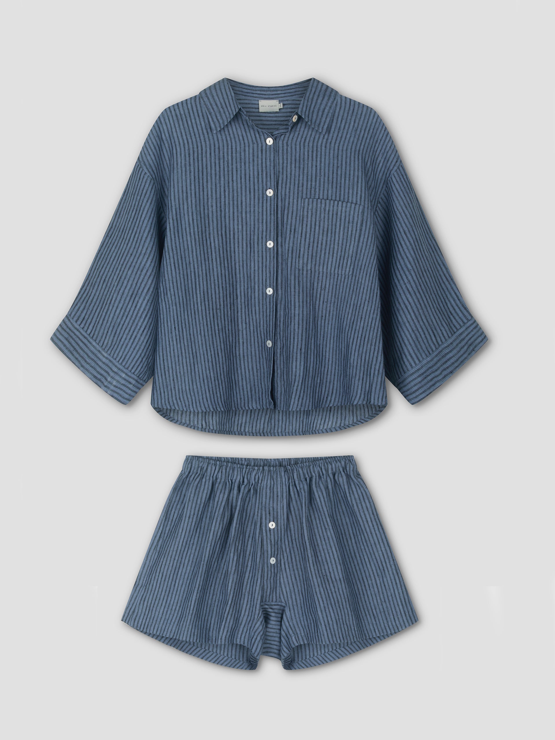 The 03 Set - Azure Stripe from Deiji Studios: blue pinstriped linen pajamas with a long-sleeve, button-up shirt and elastic-waist boxer shorts, both displayed flat on a white background.