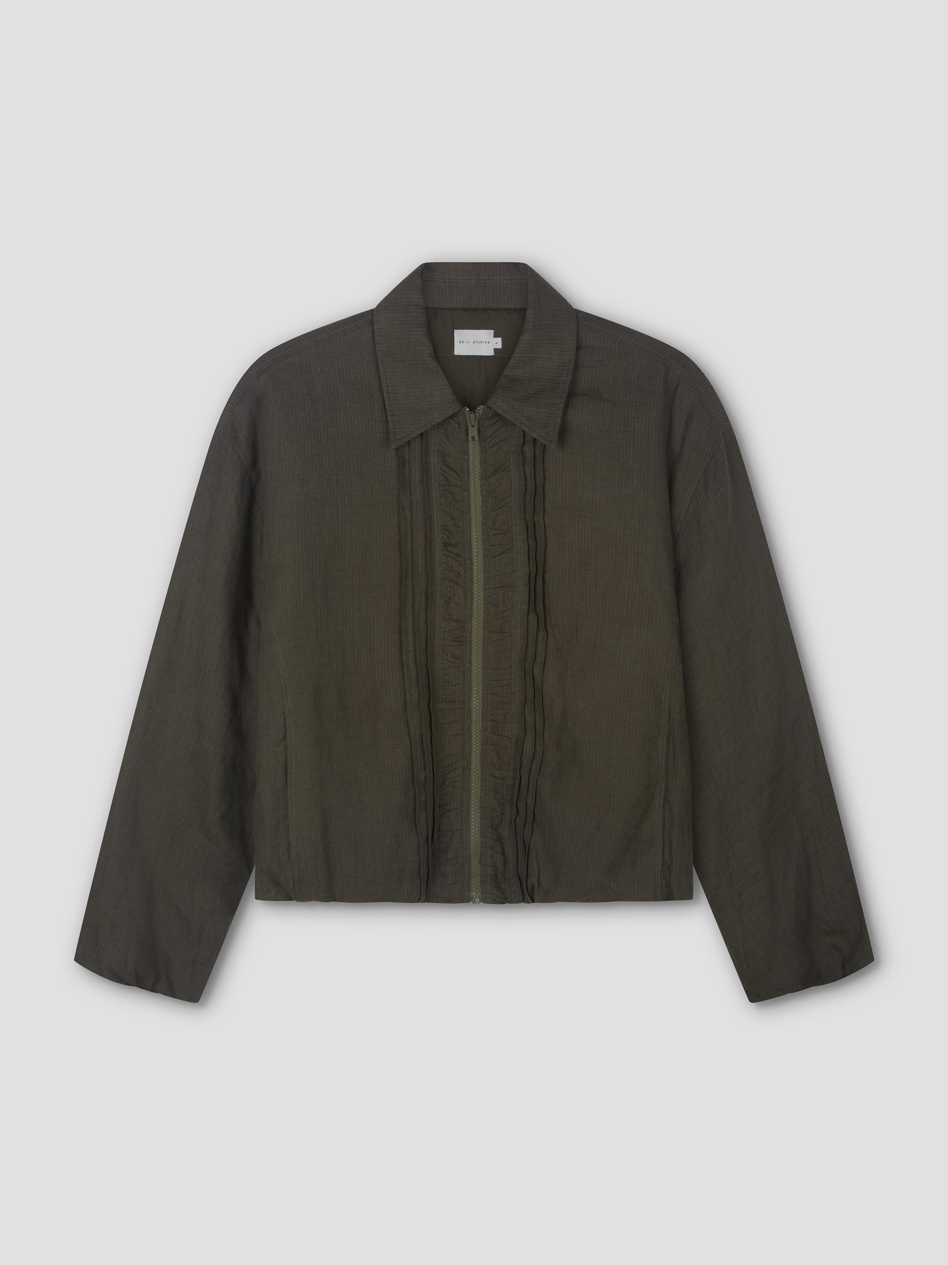 The Pintuck Jacket - Khaki Stripe by Deiji Studios is a dark olive green, long-sleeved bomber with a classic collar, front zip, subtle vertical ruffle details beside the zipper, and a straight hem. Shown laid flat on a light background.