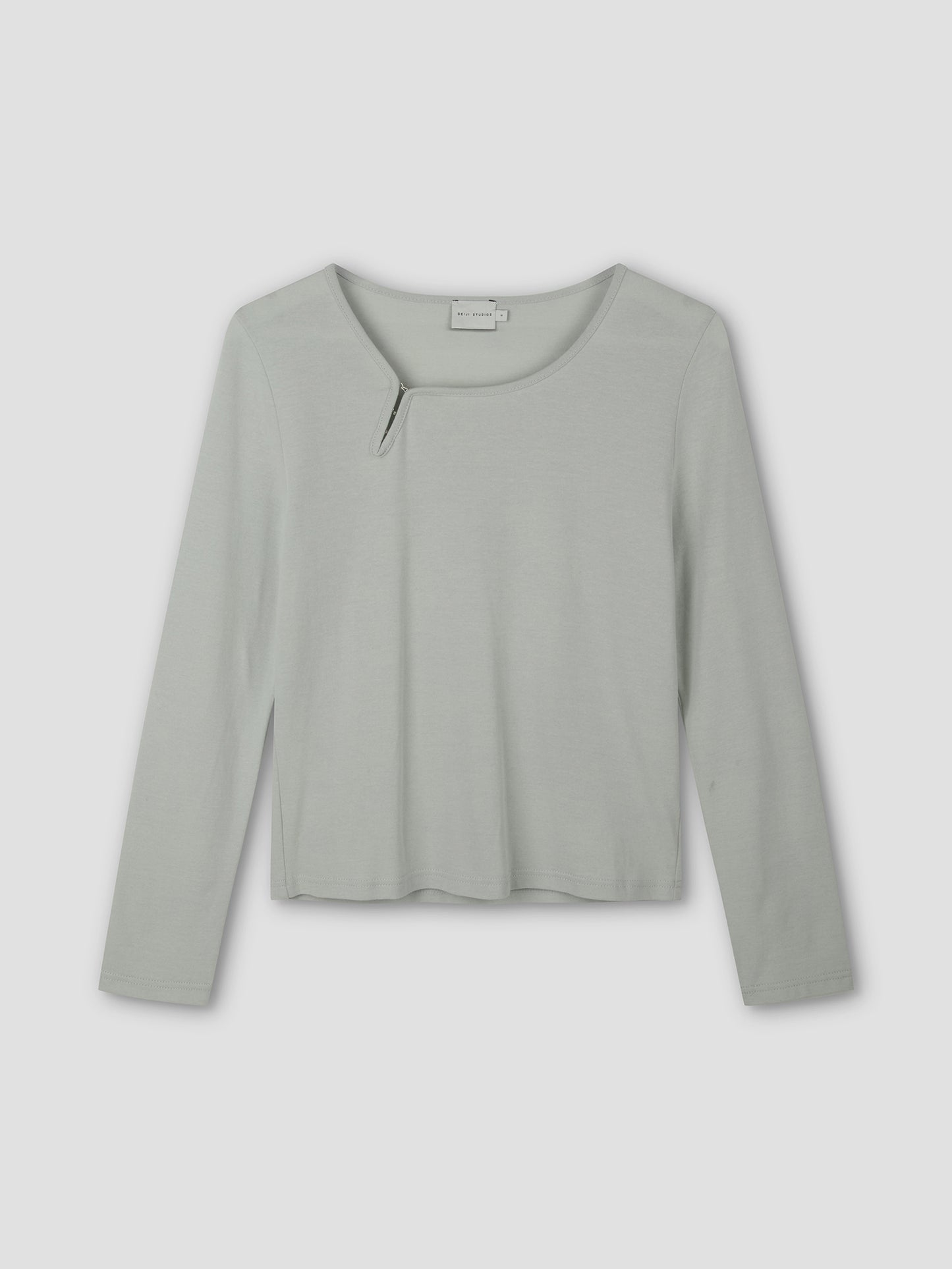The Clasp Longsleeve - Grey Blue by Deiji Studios is a light gray-blue long-sleeve top featuring a round neckline with a small angled slit detail, shown laid flat on a plain background.