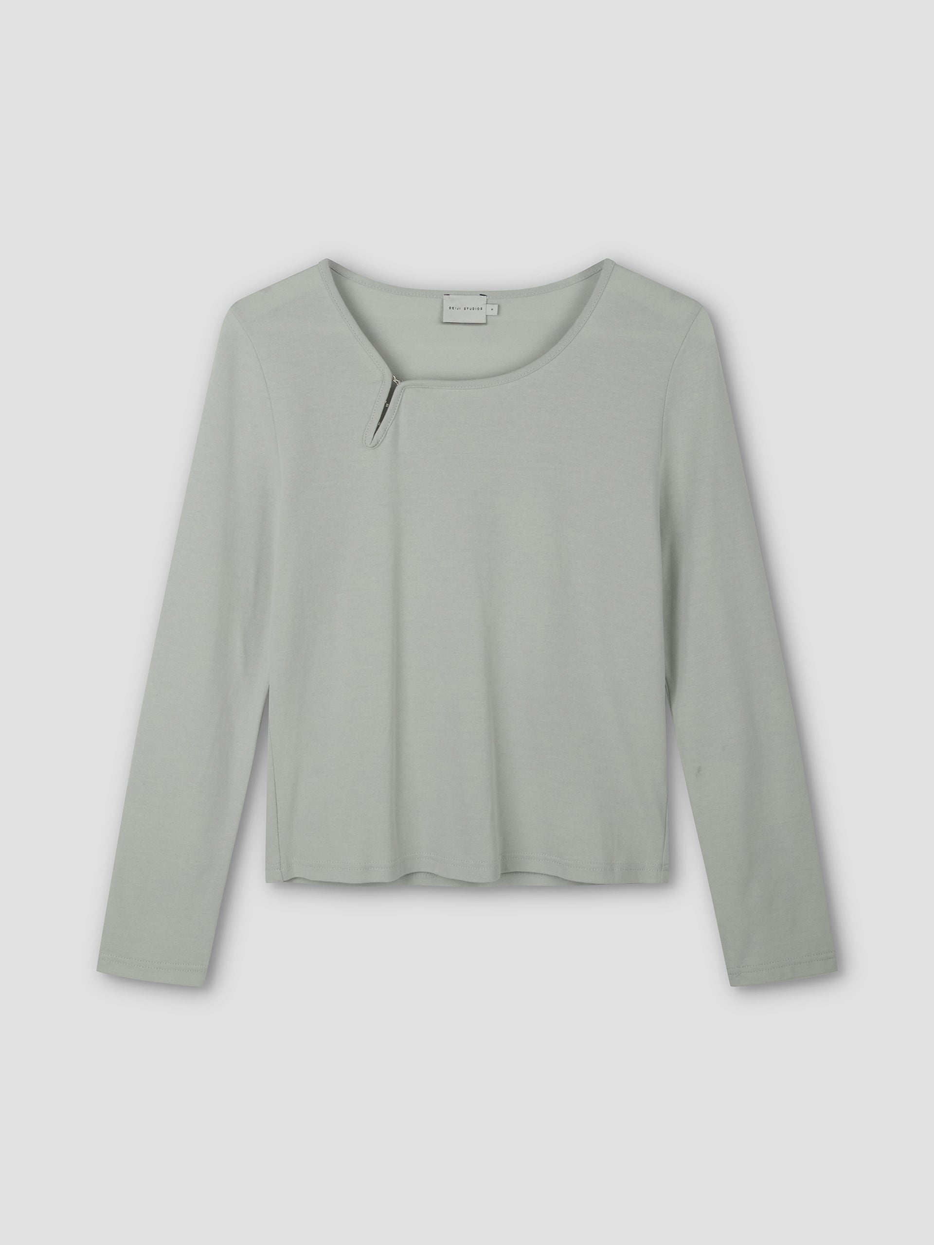 The Clasp Longsleeve - Grey Blue by Deiji Studios is a light gray-blue long-sleeve top featuring a round neckline with a small angled slit detail, shown laid flat on a plain background.