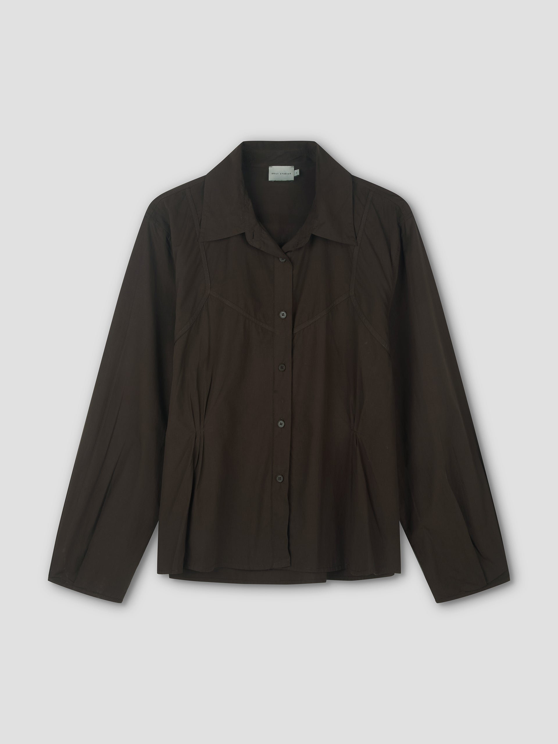 The Cami Overshirt in Sepia is a lightweight, long-sleeved button-up with a pointed collar and subtle pleat details, shown against a plain light background.