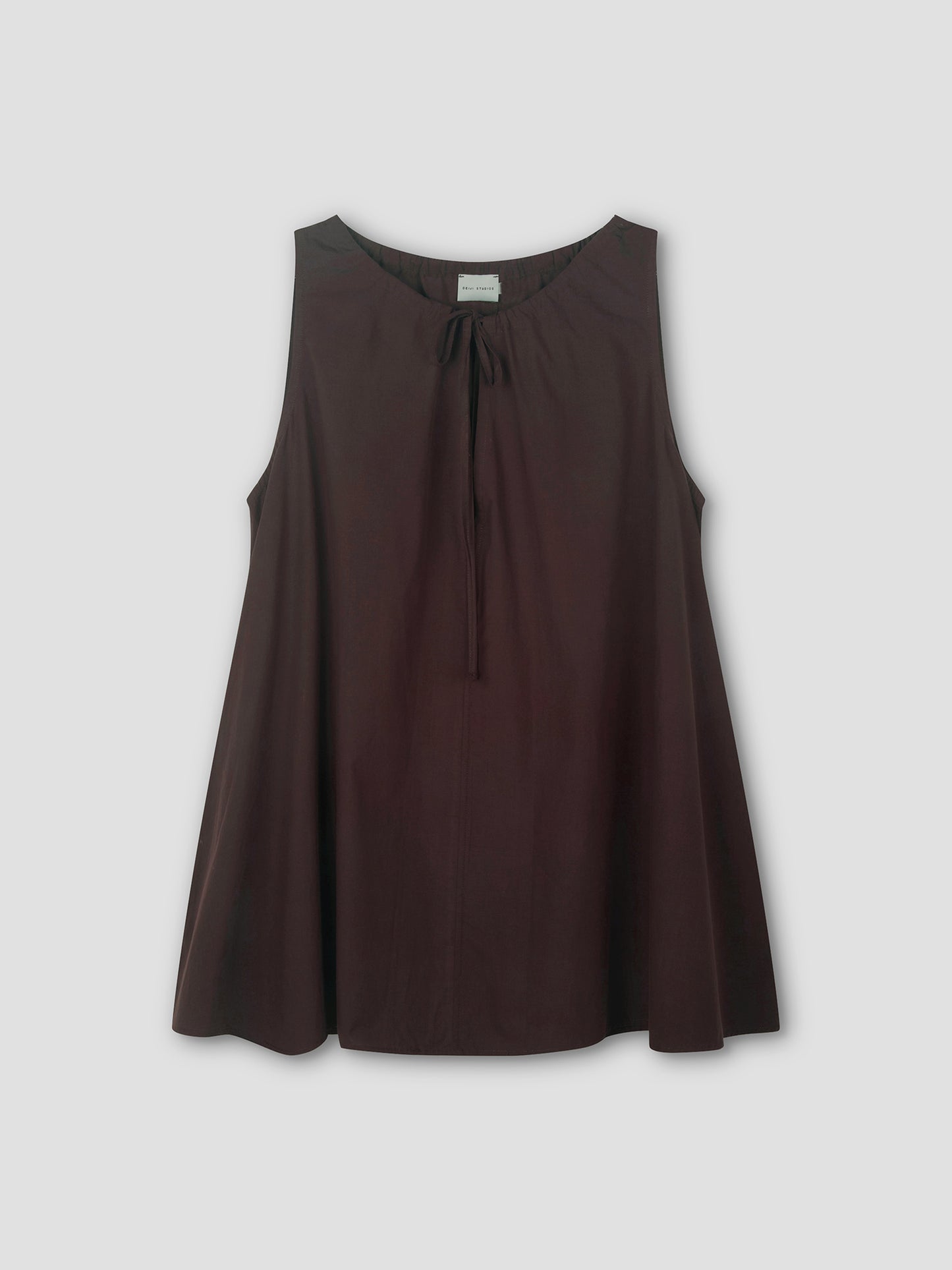 The Drawcord Dress in sepia is sleeveless and loose-fitting, with a round neckline and tie detail, featuring an A-line silhouette. Shown against a light grey background.