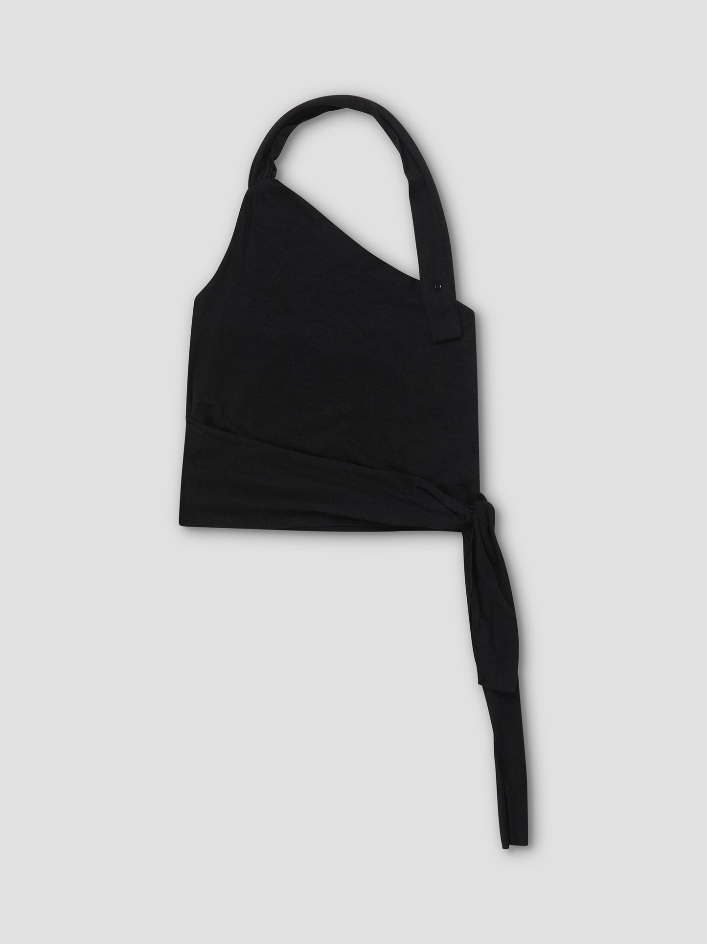 The Drape Halter - Black is an asymmetrical one-shoulder crop top with a thick strap and long waist tie, subtle gathered neckline, shown flat on a light gray background.