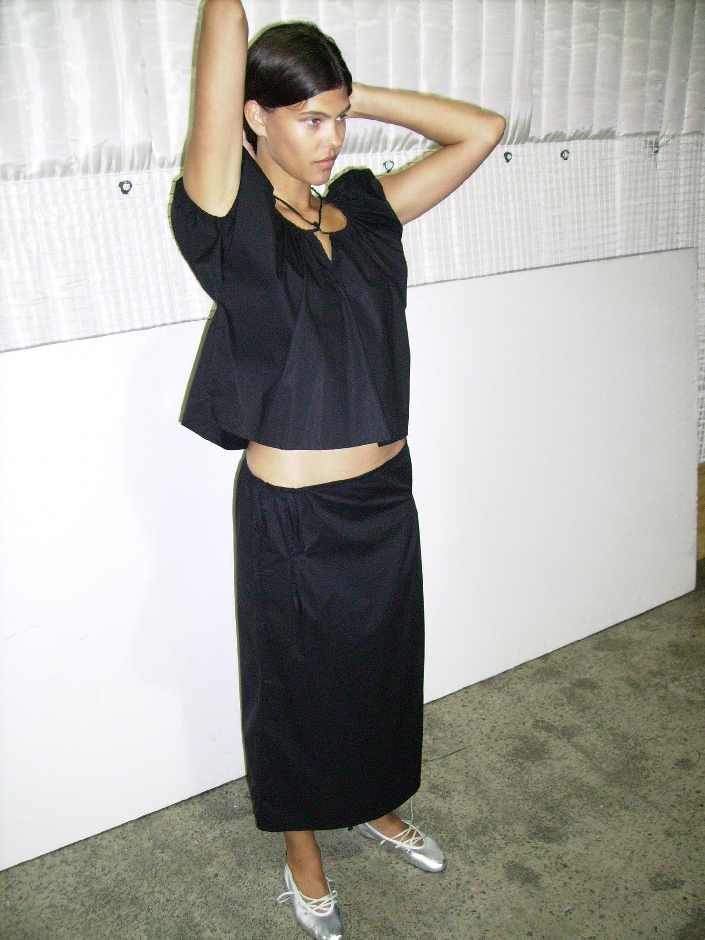 Female model wearing One Panel Top - Black by Deiji Studios against plain background
