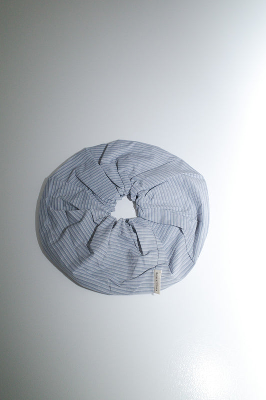 The Scrunchie - Sky Stripe from Deiji Studios, made of oversized organic cotton in light blue and white stripes, is arranged in a circular shape on a plain white surface.