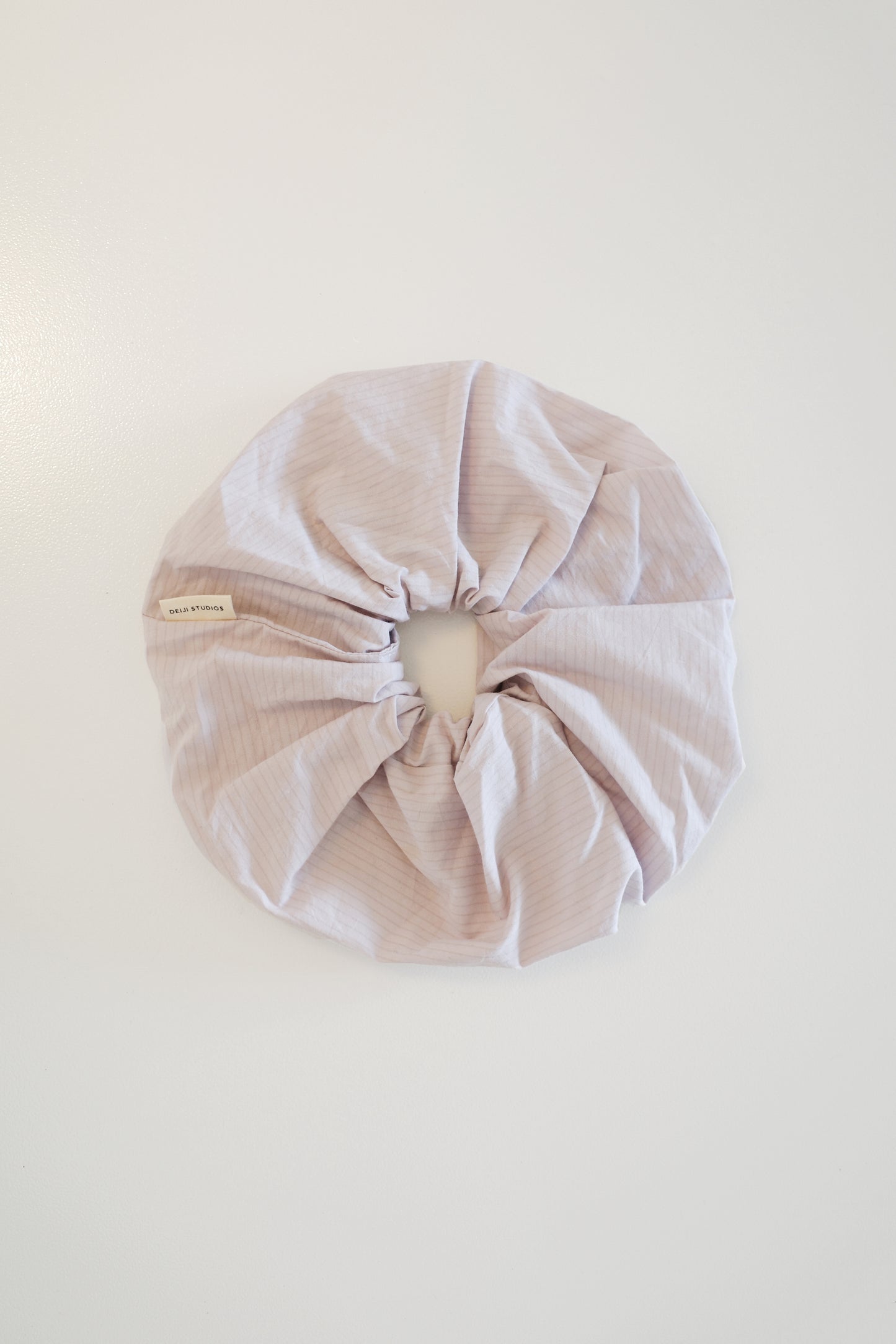 The Scrunchie - Lilac Stripe, an oversized organic cotton hair tie with subtle pale lavender stripes, is shown against a plain white background.