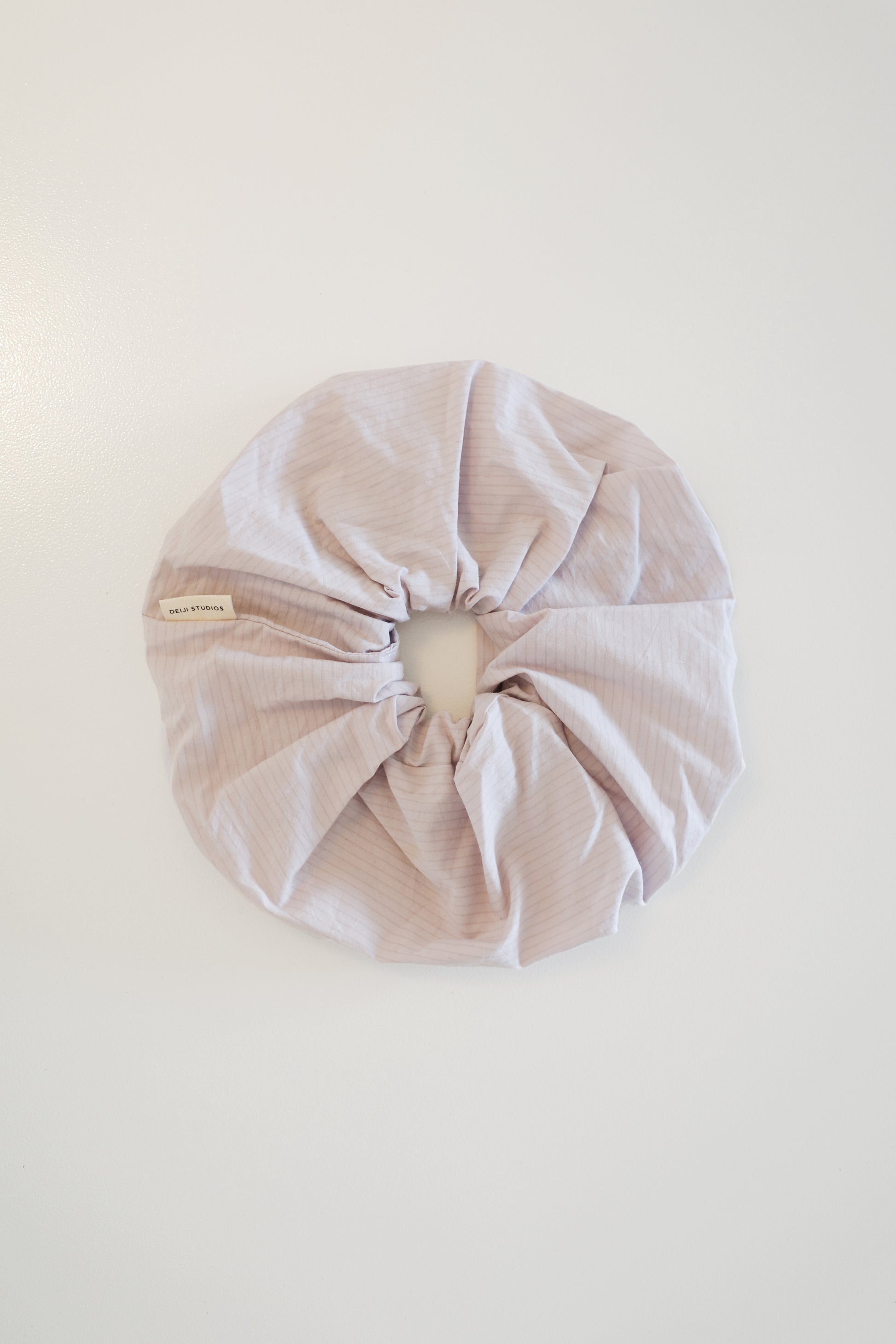 The Scrunchie - Lilac Stripe, an oversized organic cotton hair tie with subtle pale lavender stripes, is shown against a plain white background.