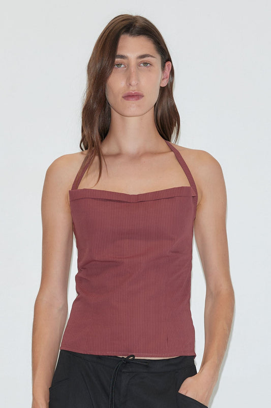 A person with long brown hair wearing the Folded Top - Rust Stripe by Deiji Studios and black pants stands against a plain white background.