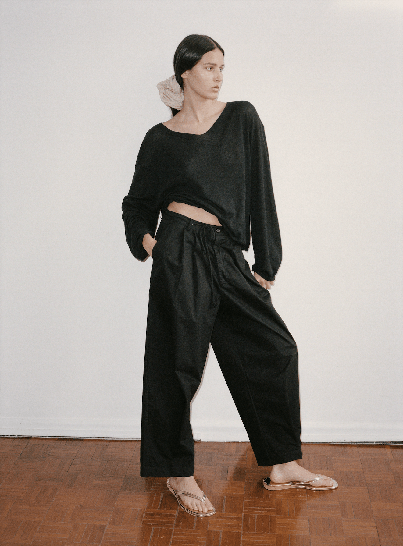 Female model wears the Deiji Studios Loose Long Sleeve Knitted Top in black, styled with the Cotton Pant in black and Scrunchie in Sand Stripe worn in hair. Pant has a drawcord waist, belt loops and a relaxed tapered leg.