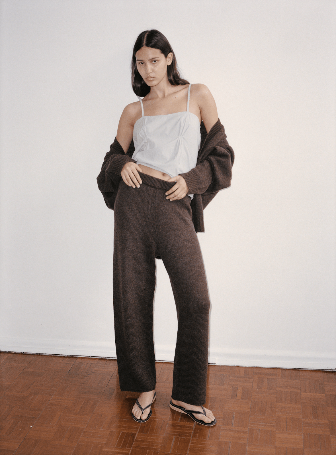 Film image of female model wearing the top from the Pleat Set in Dream Stripe, worn with the Straight Leg Knit Pants in plum and Two Tie Cardigan in plum worn off the shoulders.