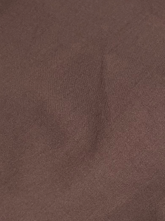 A close-up of the brown, textured organic cotton fabric with gentle folds and shadows highlights the soft, lightly uneven surface—ideal for the Napkin Belt - Chocolate by Deiji Studios.