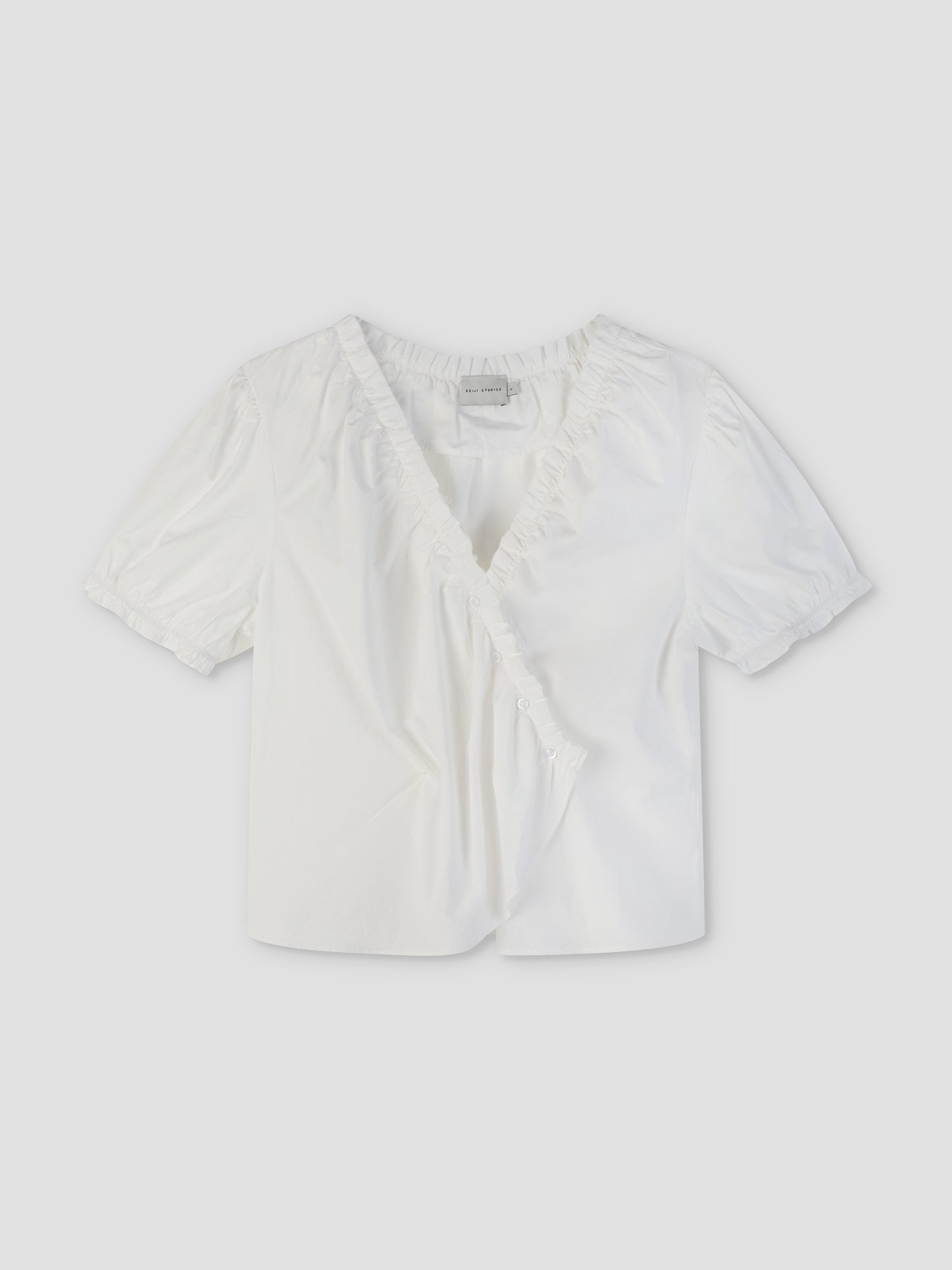 The Cross Frill Top - White features short sleeves, a V-neckline with ruffle trim, a buttoned wrap front, and a cropped relaxed fit in crisp fabric for effortless style.