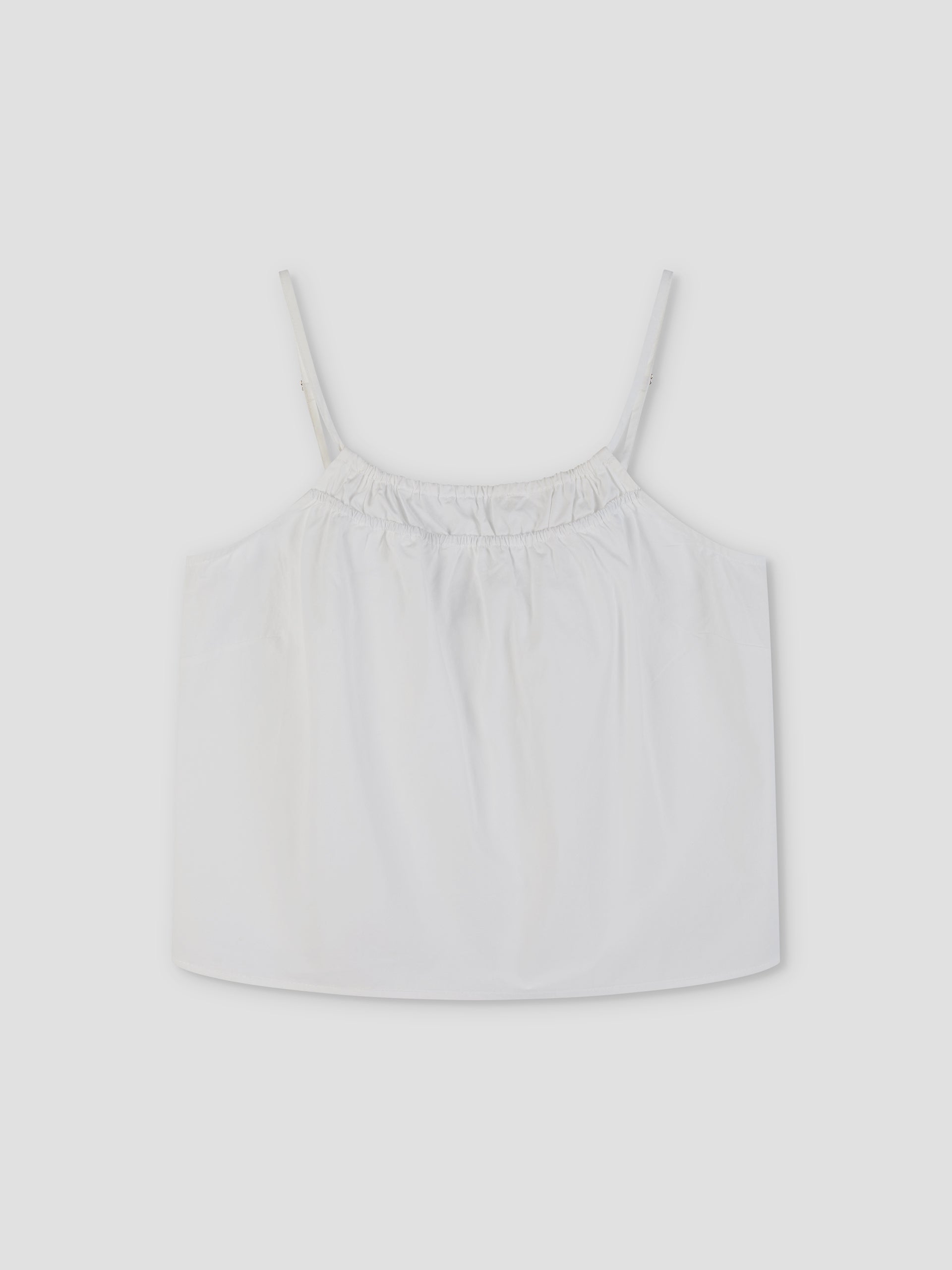 The Double Layer Top - White by Deiji Studios is a white, sleeveless cami with thin adjustable straps and an elasticized gathered neckline, shown laid flat on a light gray background.