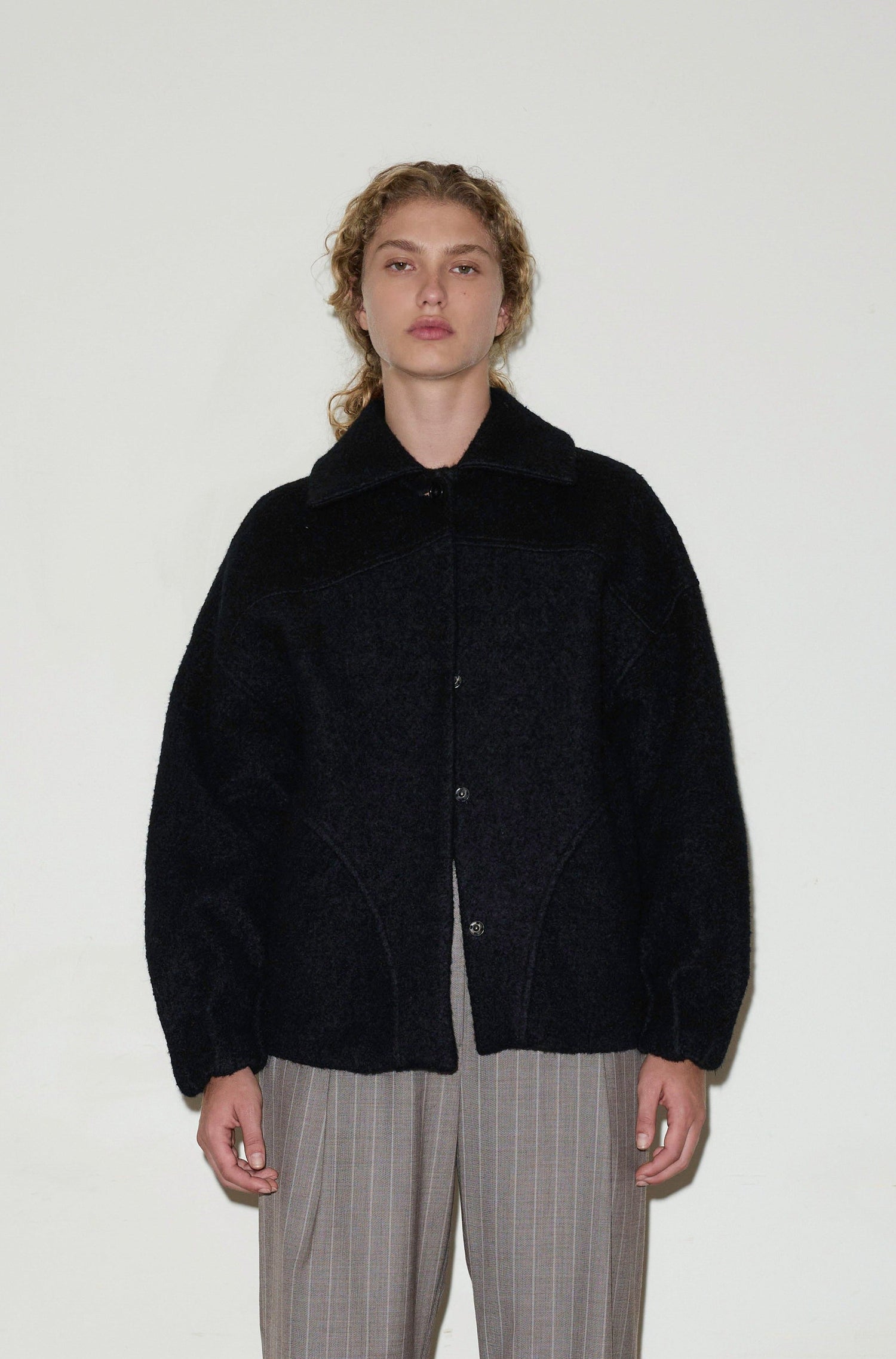 Female model wearing Boiled Wool Coat - Black by Deiji Studios against plain background