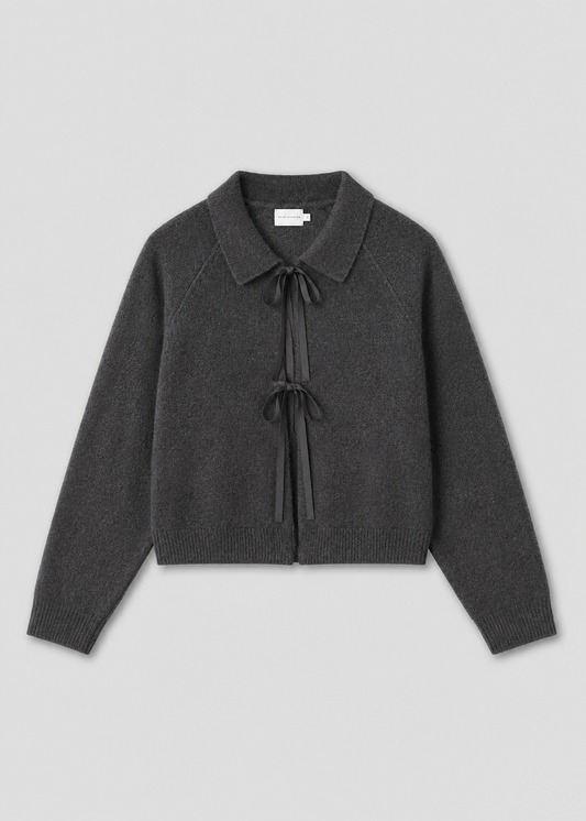 The Box Cardigan - Charcoal is a long-sleeved knit with a collar and two black ribbon ties on the front, inspired by Deiji Studios and shown on a light gray background.