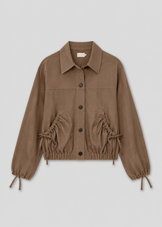 The Button Up Jacket - Brown is a light brown cropped jacket with a collar, front buttons, drawstring waist and cuffs, elastic hem, and two large front pockets, shown on a plain light background.