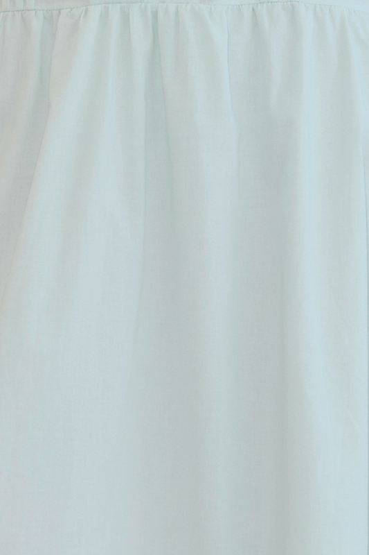 A close-up of light blue organic cotton fabric with a gathered ruched seam near the top edge, as seen on the Button Frill Top – Mint.