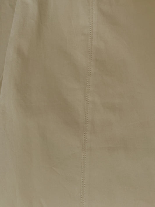 A close-up of the Pocket Pant - Stone by Deiji Studios shows beige organic cotton fabric with a vertical center seam, highlighting its texture and detailed stitching.