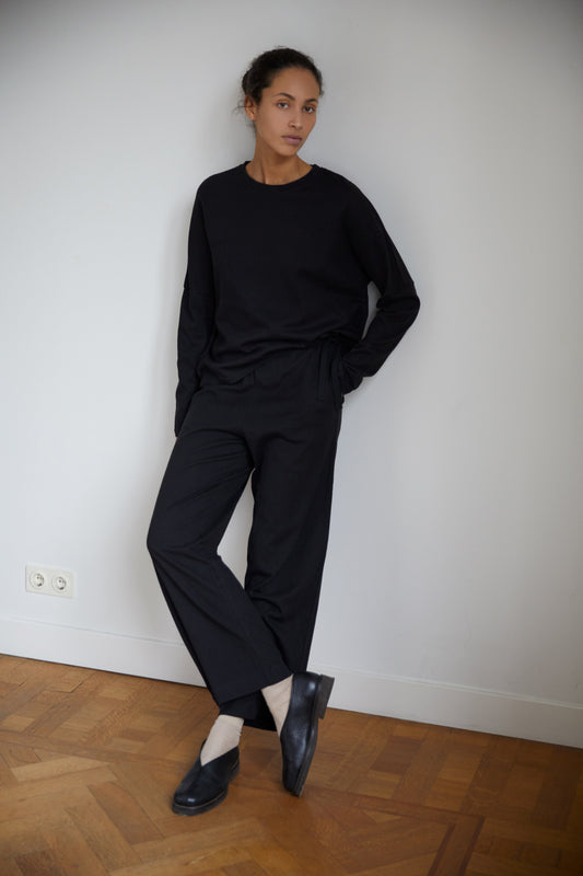 Female model wearing the long sleeve jersey top - black by Deiji Studios against plain background