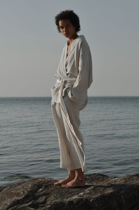 Female model wearing the 01 set - oatmeal by Deiji Studios against ocean horizon